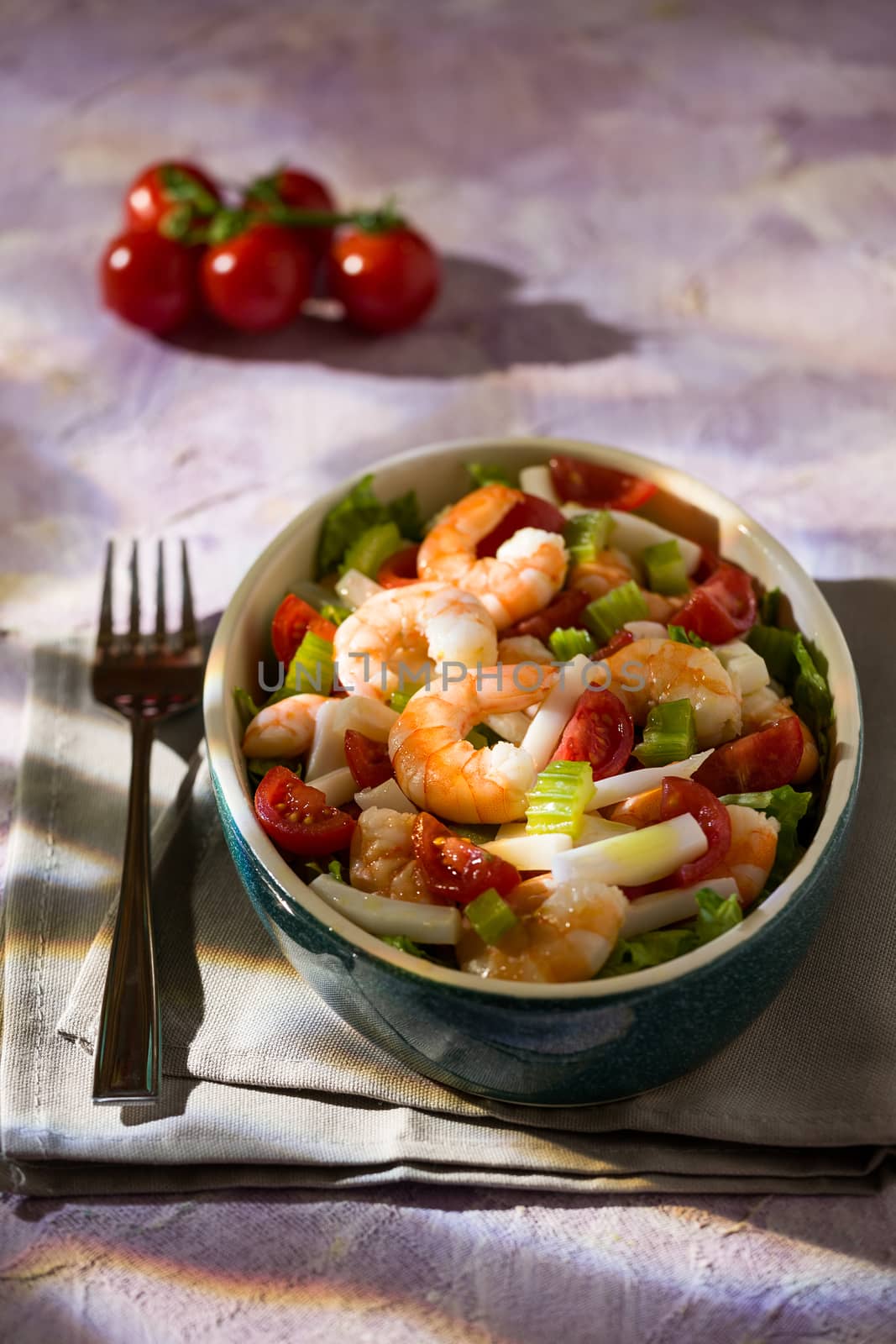 Salad of shrimps with squid tomatoes celery inside an oval bowl
