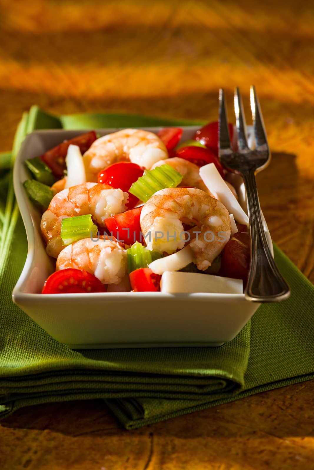 Shrimp salad with squid tomatoes celery inside a white bowl