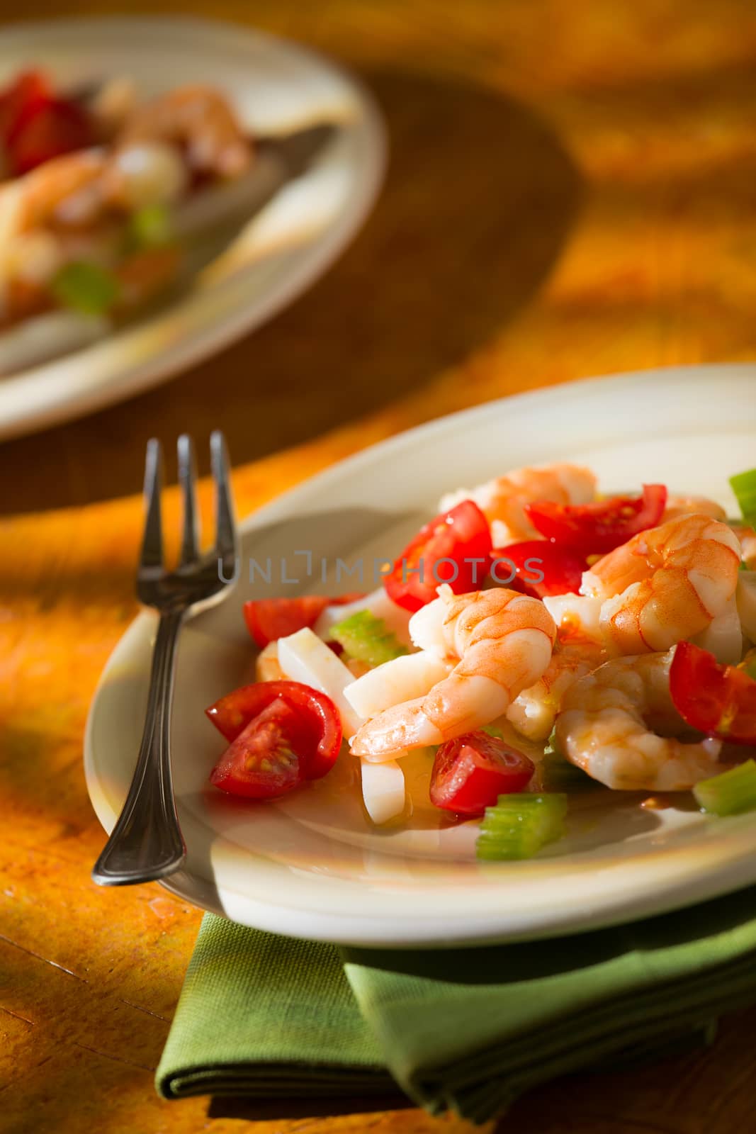 Shrimp salad with squid tomatoes and celery over a green napkin with an orange background