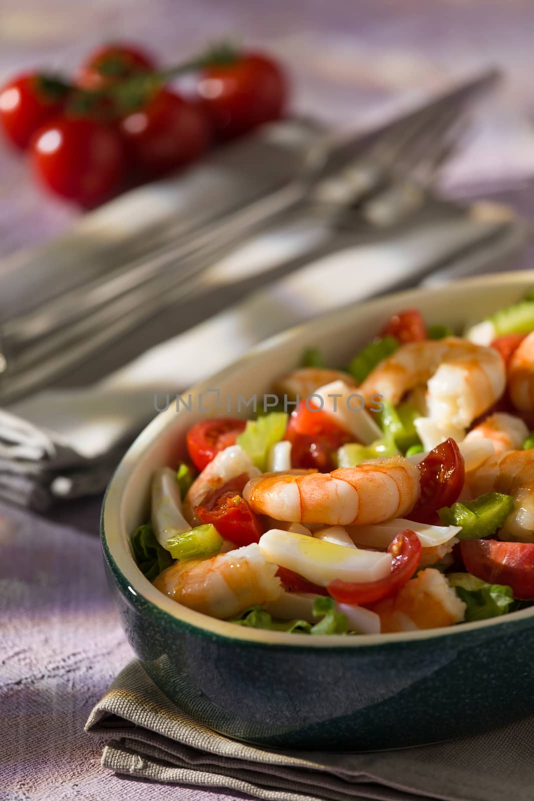 Shrimp salad with squid tomatoes celery inside an oval bowl