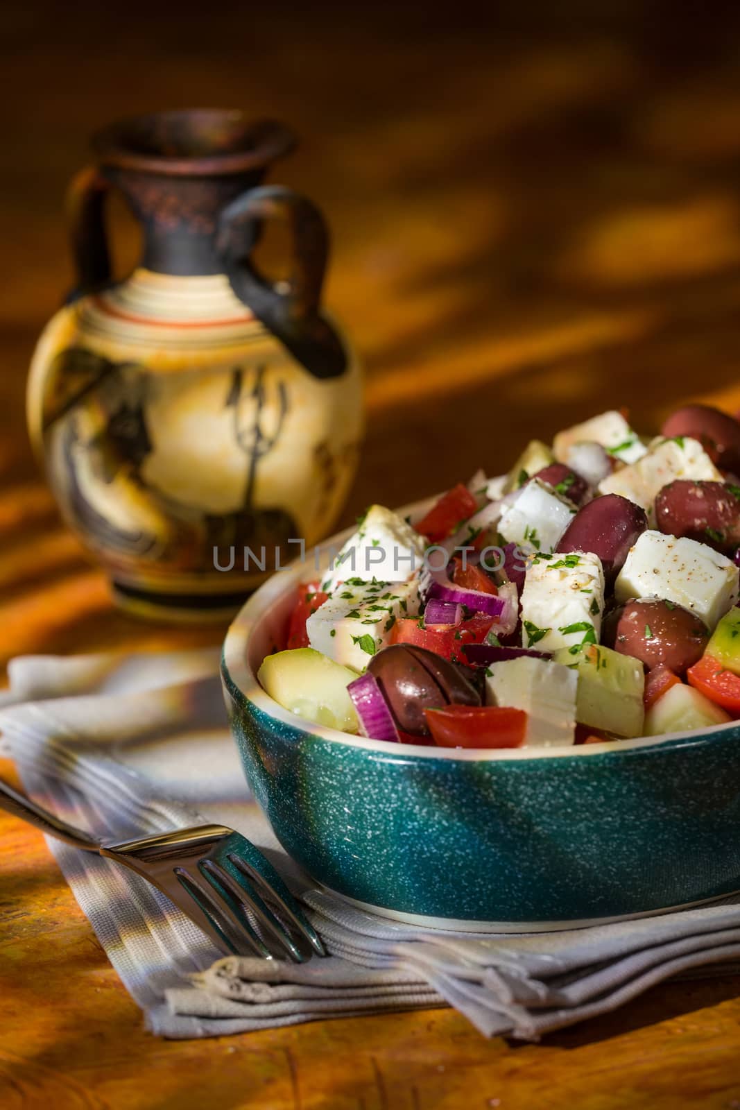 Greek salad with feta cheese tomatoes cucumber olives and onions with greek amphora with a colored background