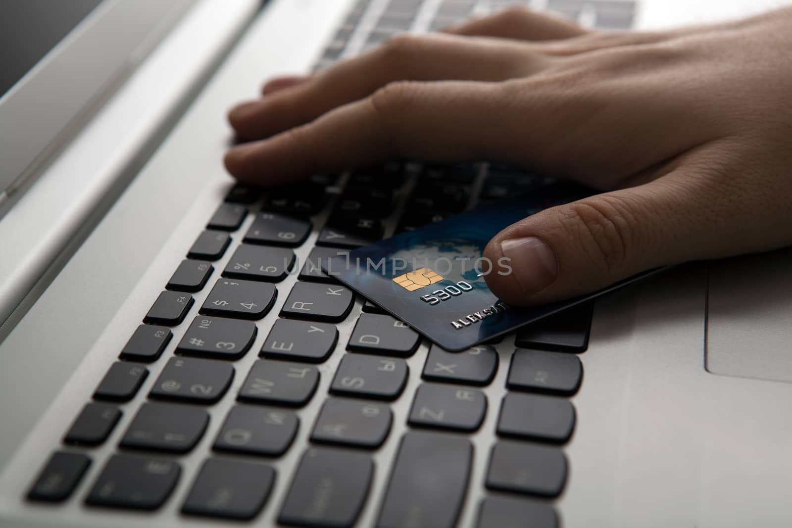 Hands holding a credit card and using laptop computer close up