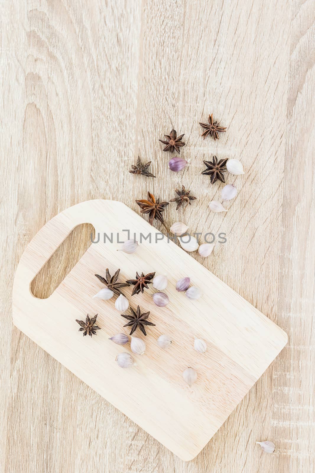 Star anise spice fruits and seed and garlic on wood chopping board and wood table from above