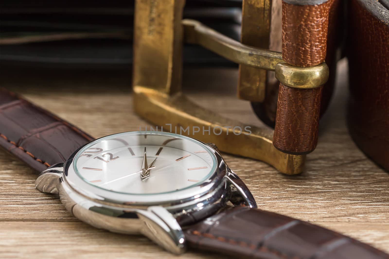 Close up wristwatch and brown leather belt on wood table