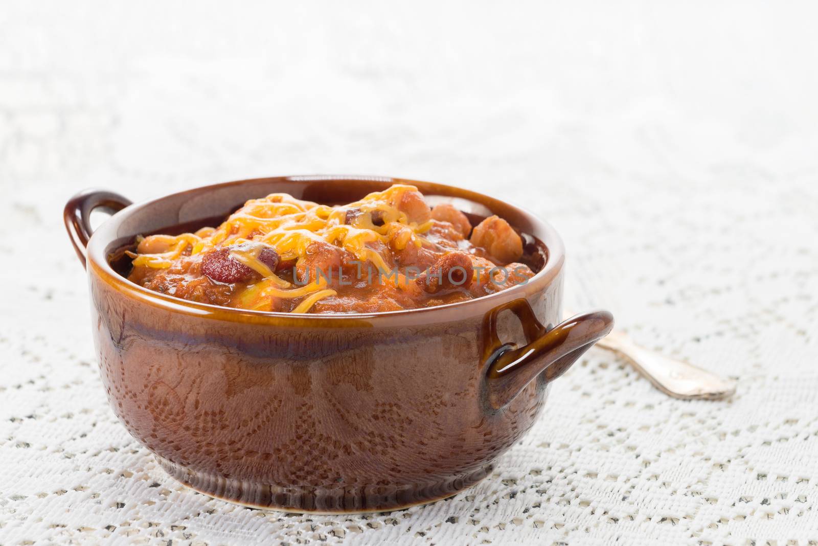 Bowl of hearty vegetarian chili topped with melted cheese.
