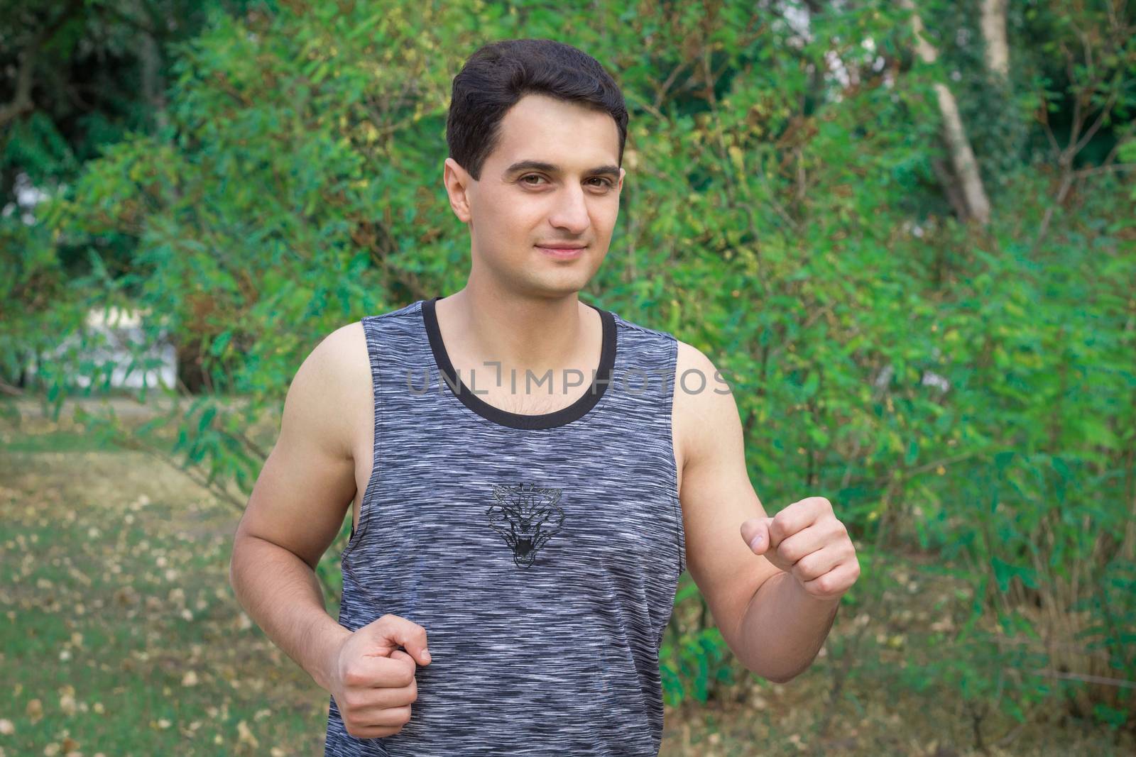 Young fitness man runs during his training workout in park outdoor