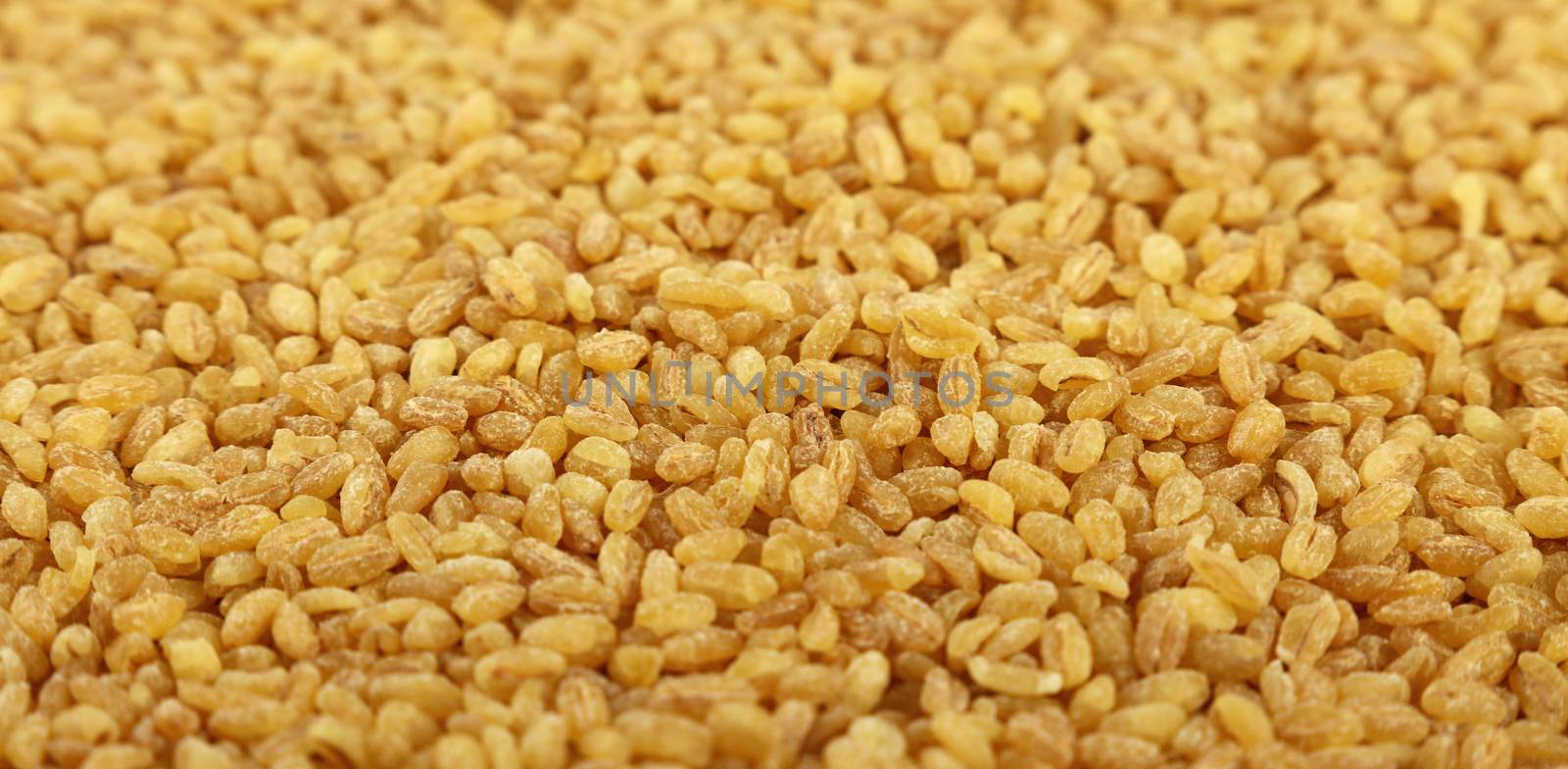 Yellow bulgur big grains close up background by BreakingTheWalls