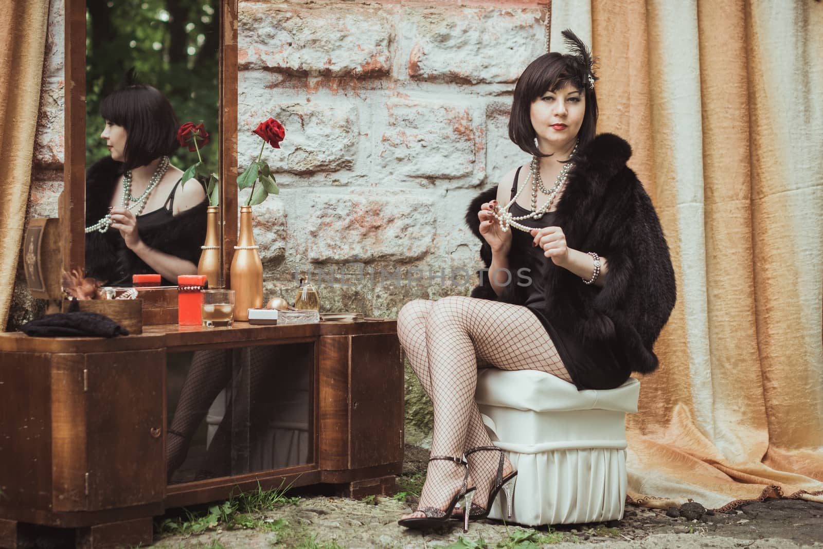 retro girl sitting at a dressing table and holding a necklace in hands