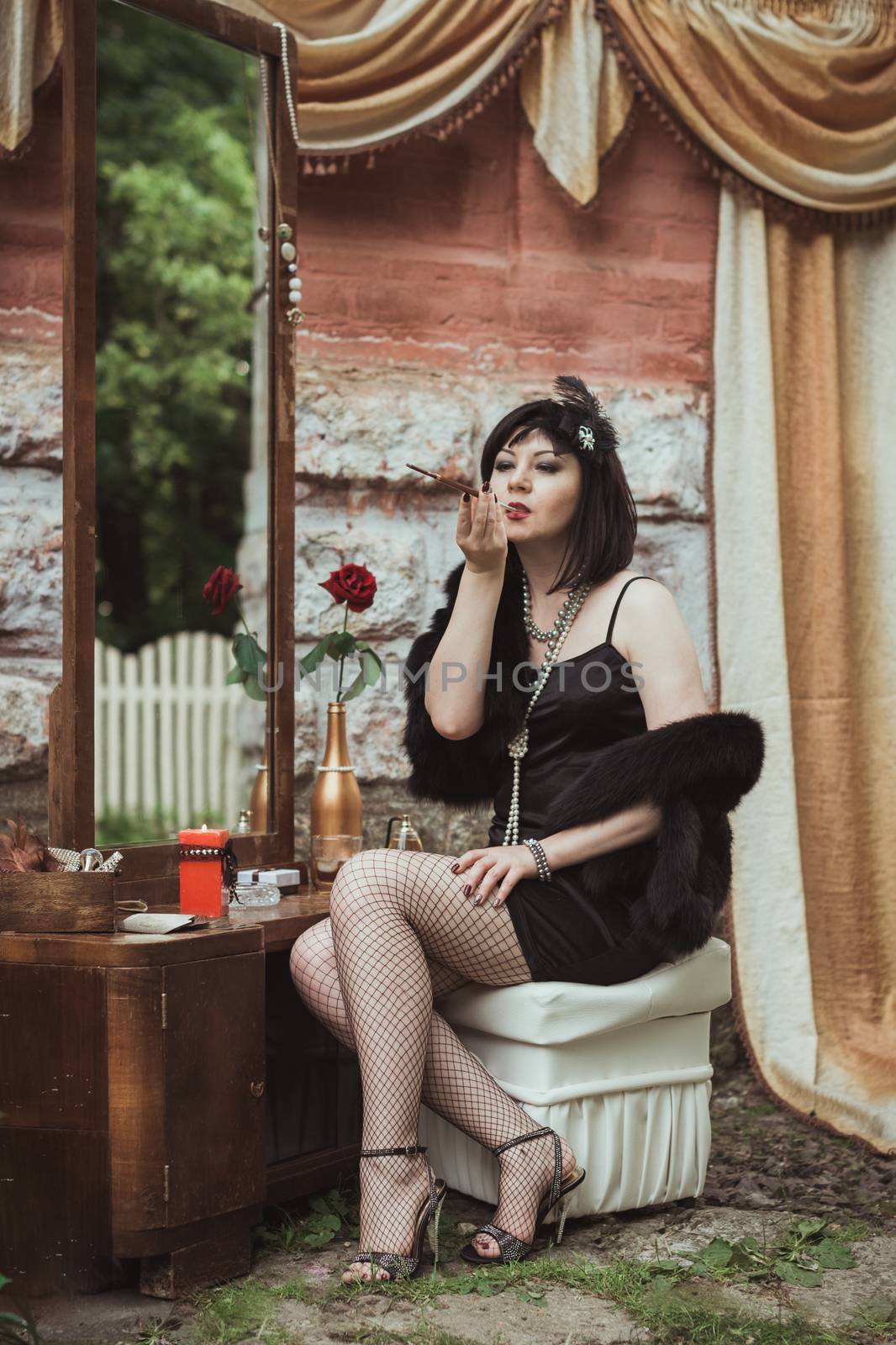 retro girl sitting at a dressing table and smoking cigarette with mouthpiece