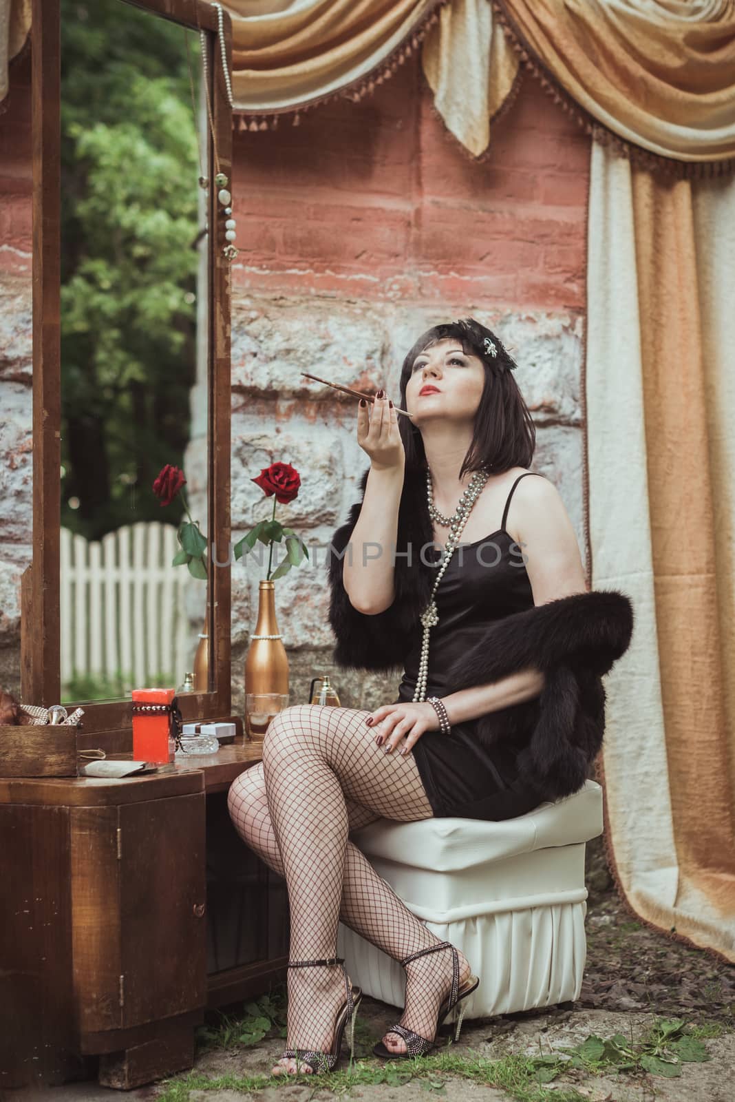 retro girl sitting at a dressing table and smoking cigarette with mouthpiece
