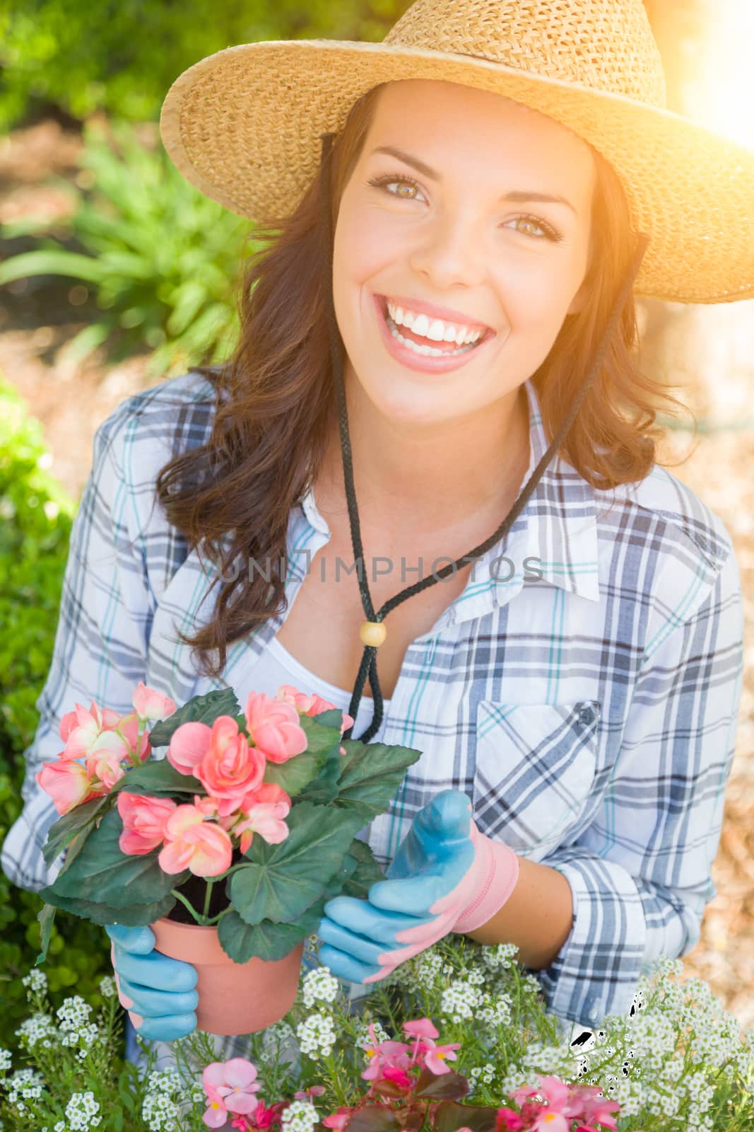 Happy Young Adult Woman Wearing Hat and Gloves Gardening Outdoors.