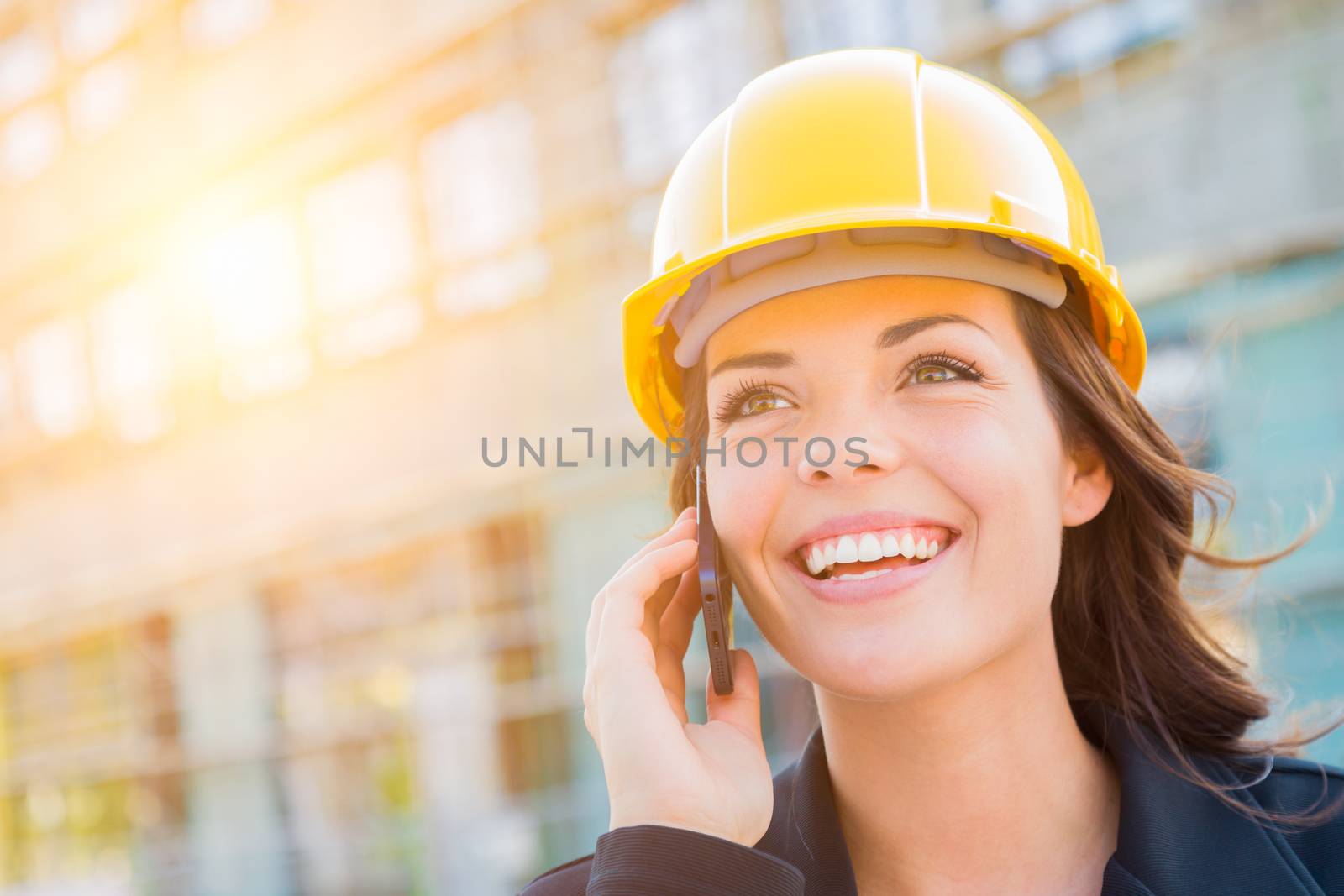 Young Female Contractor Wearing Hard Hat on Site Using Phone by Feverpitched