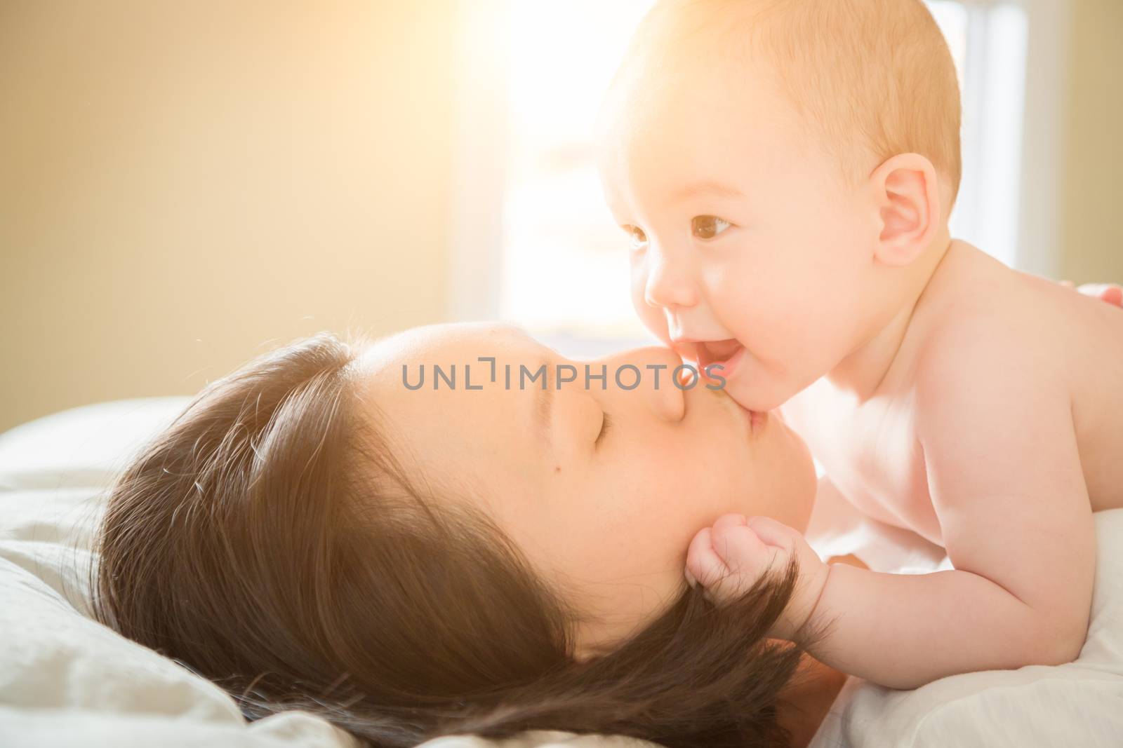 Young Mixed Race Chinese and Caucasian Baby Boy Laying In His Bed with His Mother.