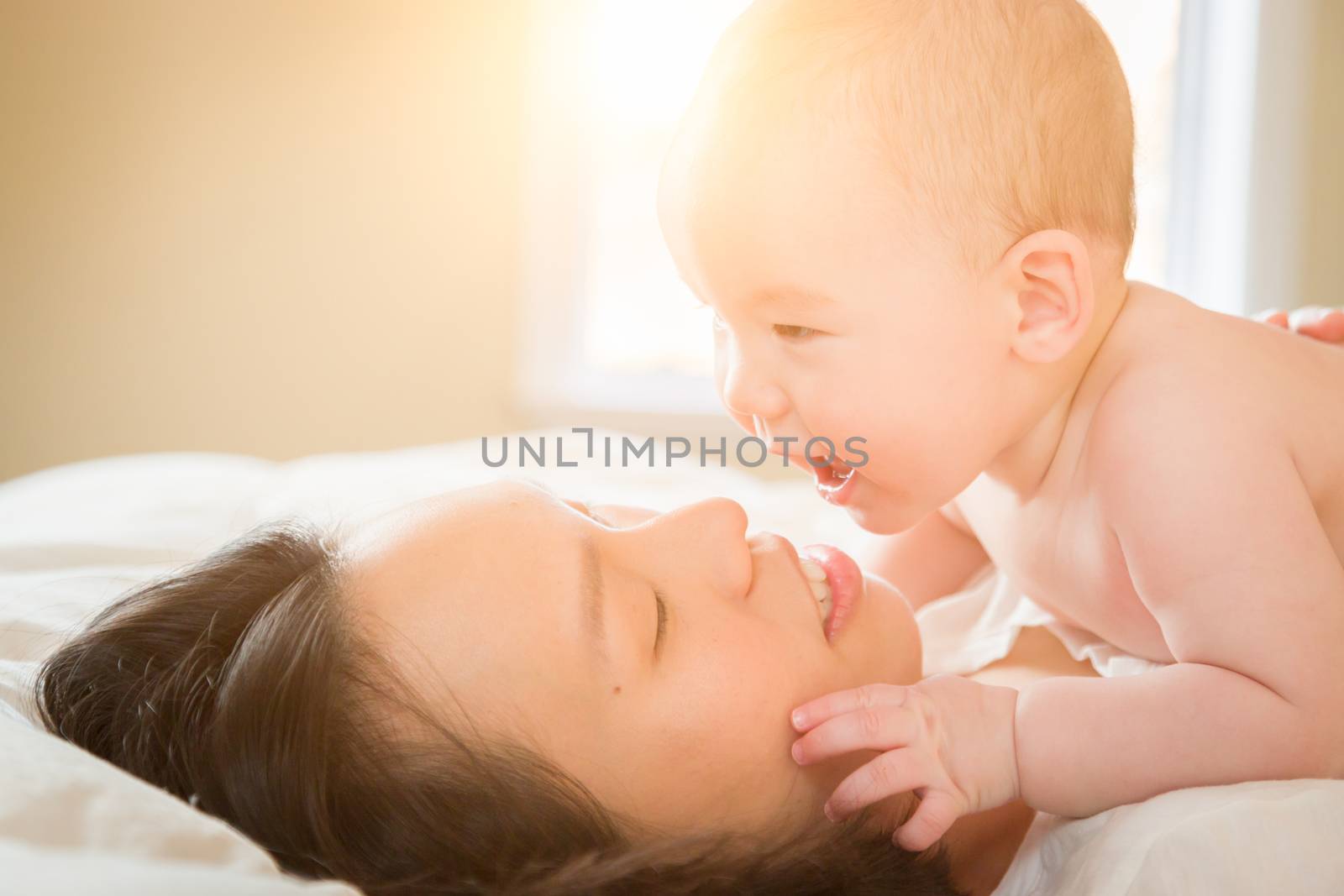 Young Mixed Race Chinese and Caucasian Baby Boy Laying In His Bed with His Mother.