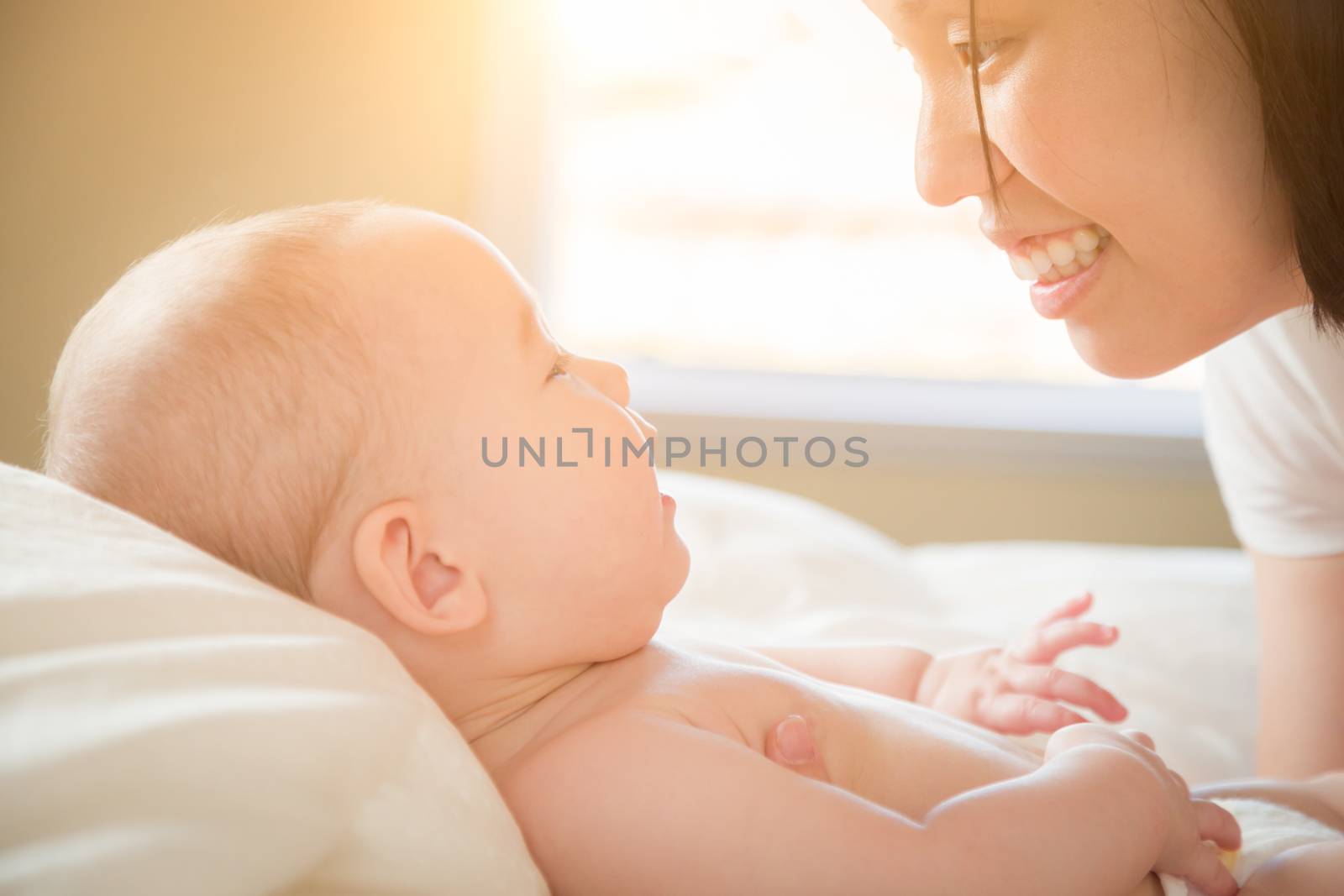 Young Mixed Race Chinese and Caucasian Baby Boy Laying In His Bed with His Mother.