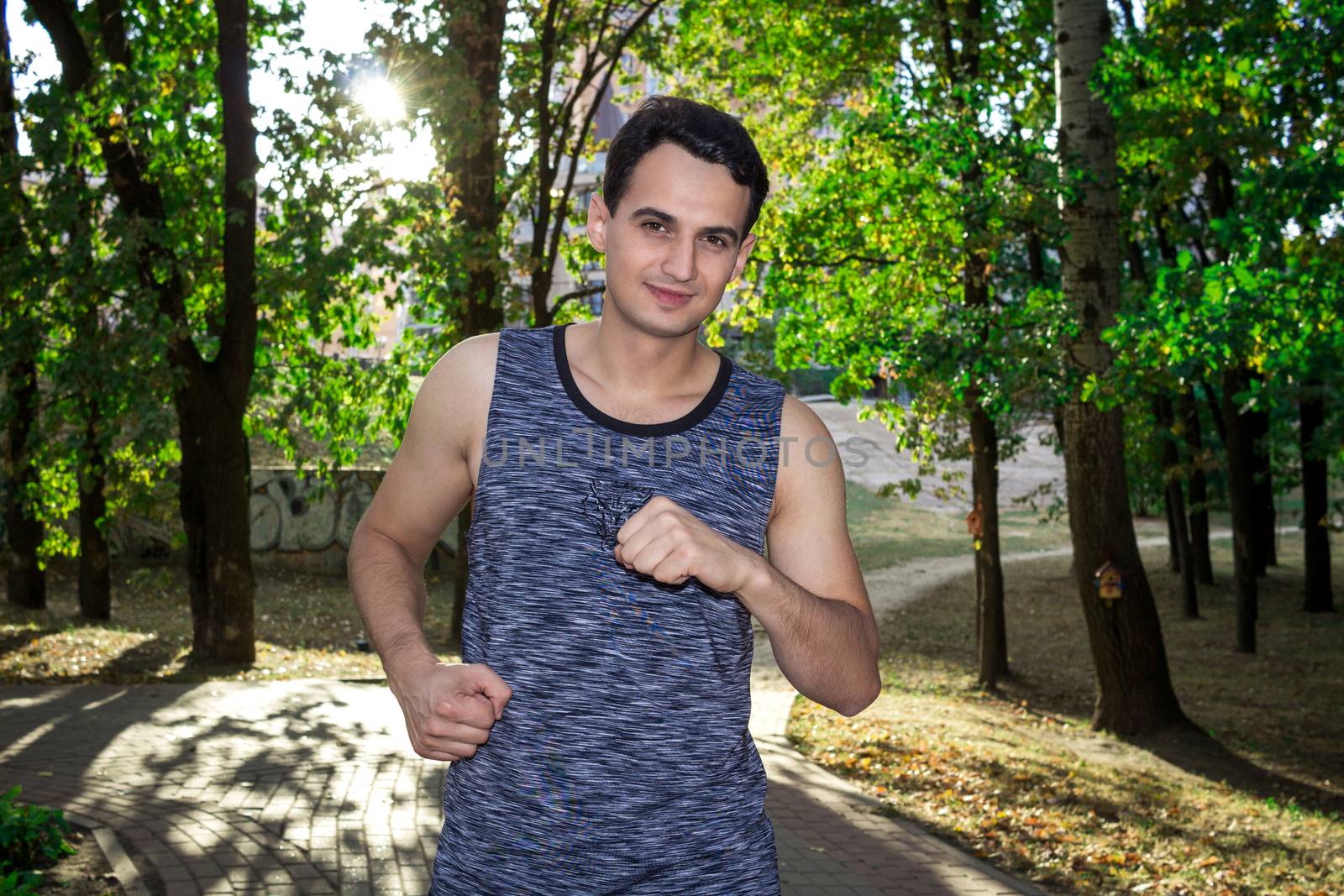 Young fitness man runs during his training workout in park outdoor