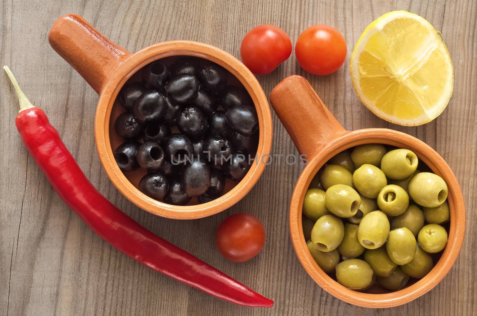 Olives in cups on a wooden table by Gaina