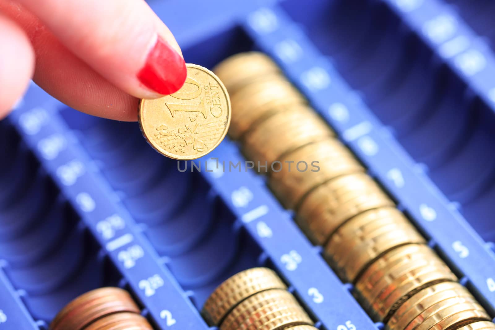 Close-up Of Hand With Euro Coins Over Container