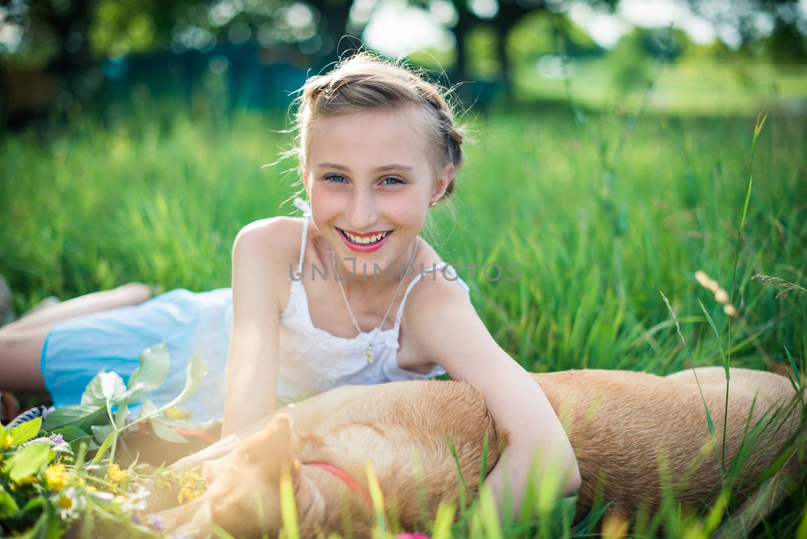 girl with a dog lying on the grass in the garden on a sunny summer day