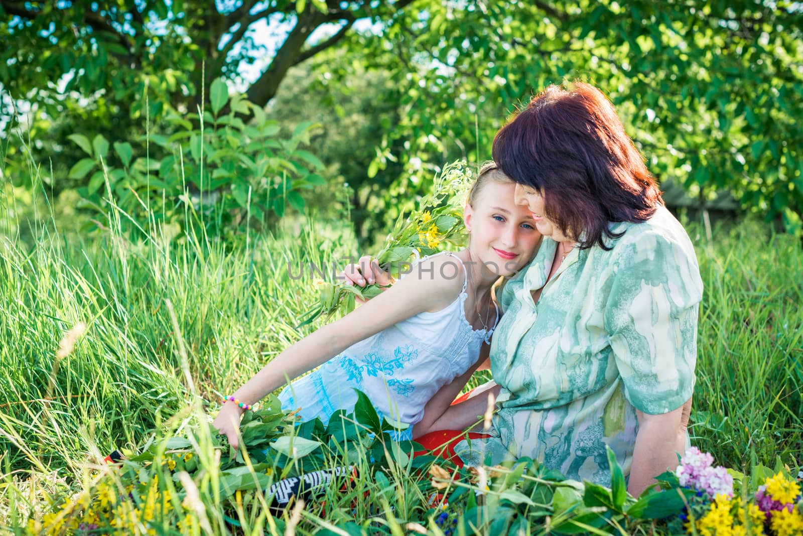 grandmother granddaughter with flowers in the green garden on a sunny summer day