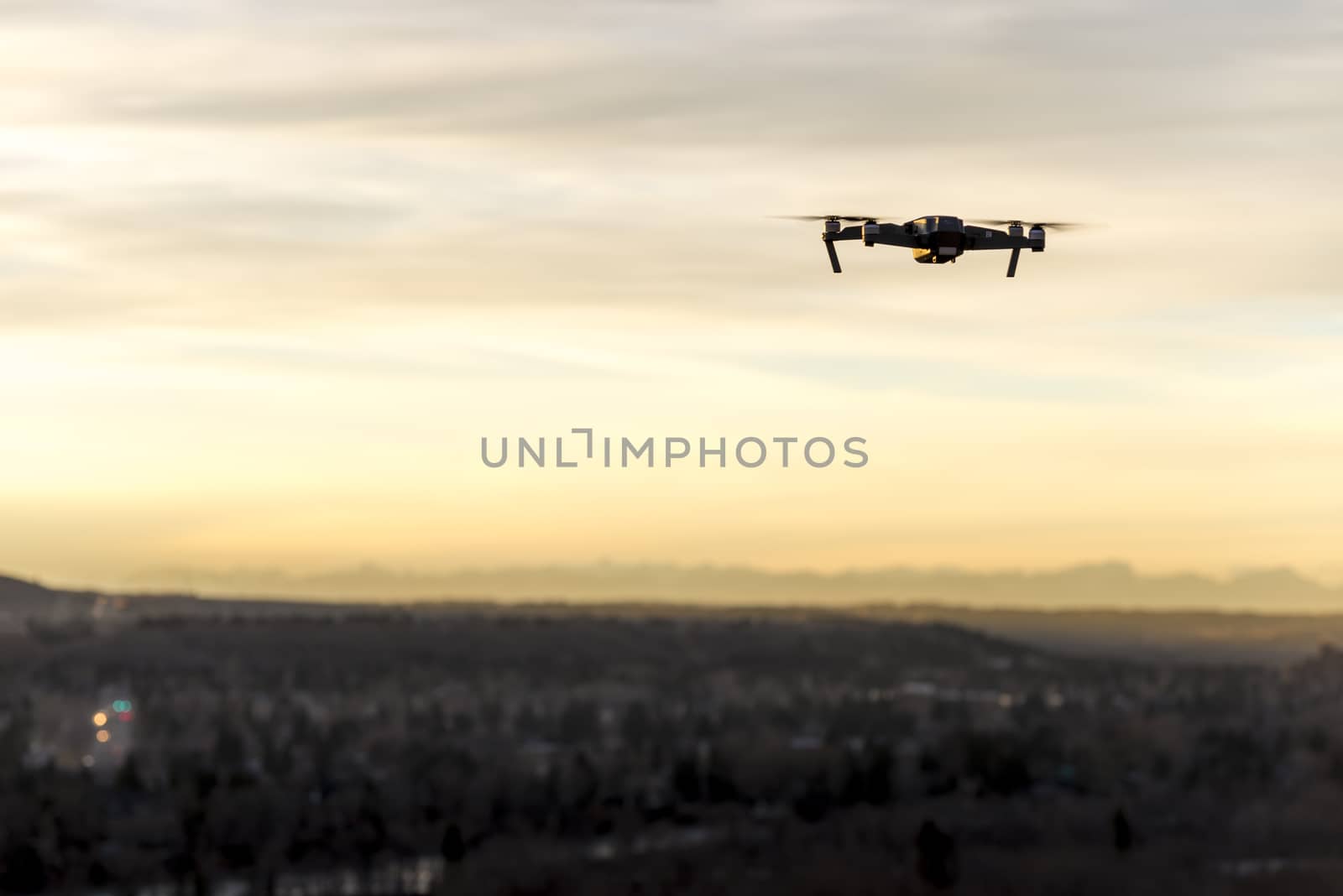 Small modern drone hovering taking picture of mountains at sunset
