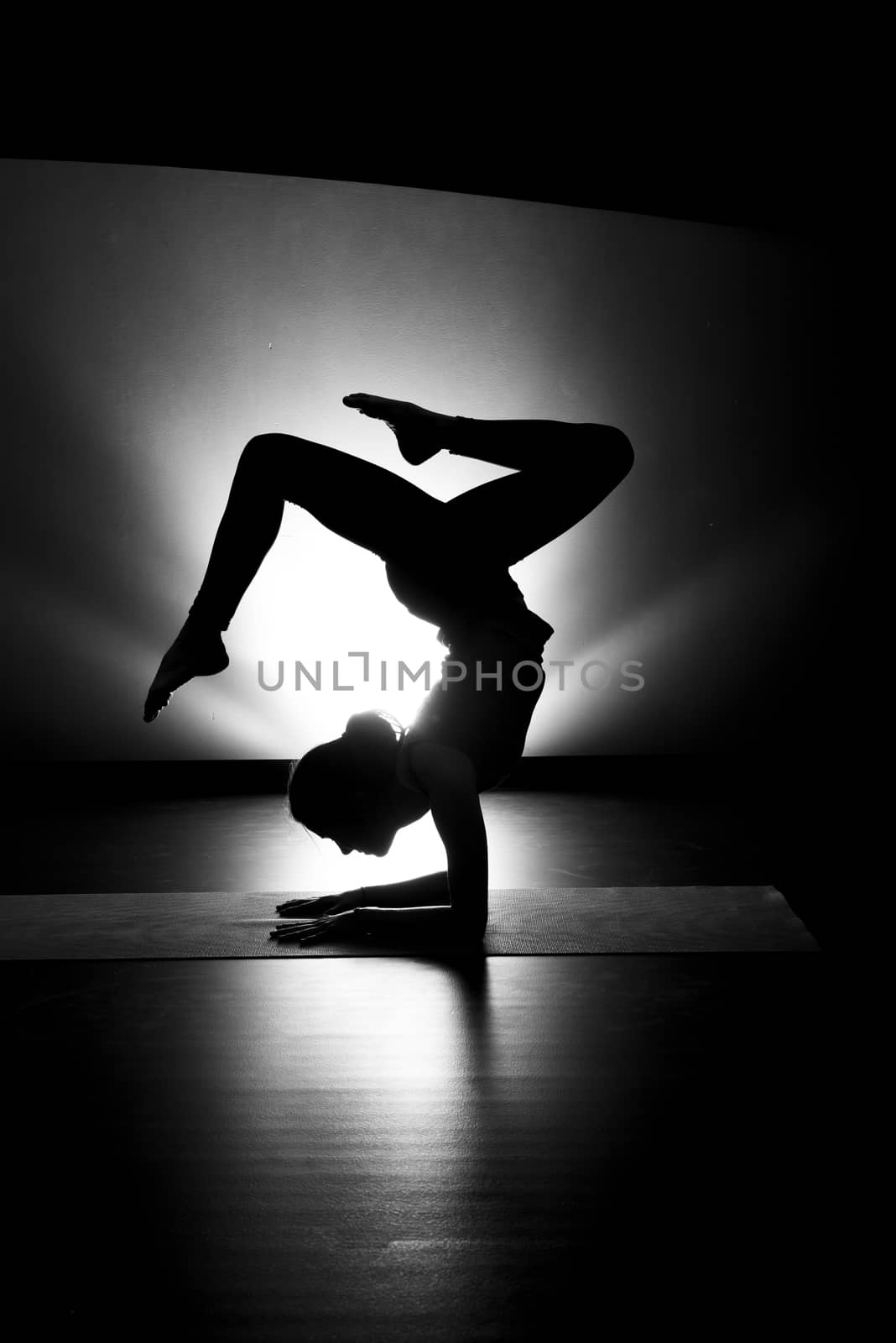 Woman doing yoga forearm stand pose silhouette black and white in studio
