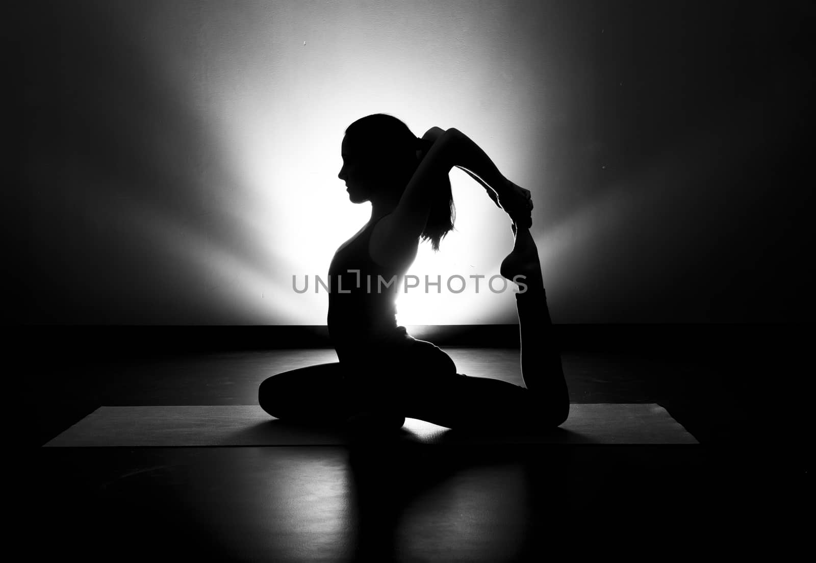 Woman doing yoga pigeon pose silhouette black and white in studio