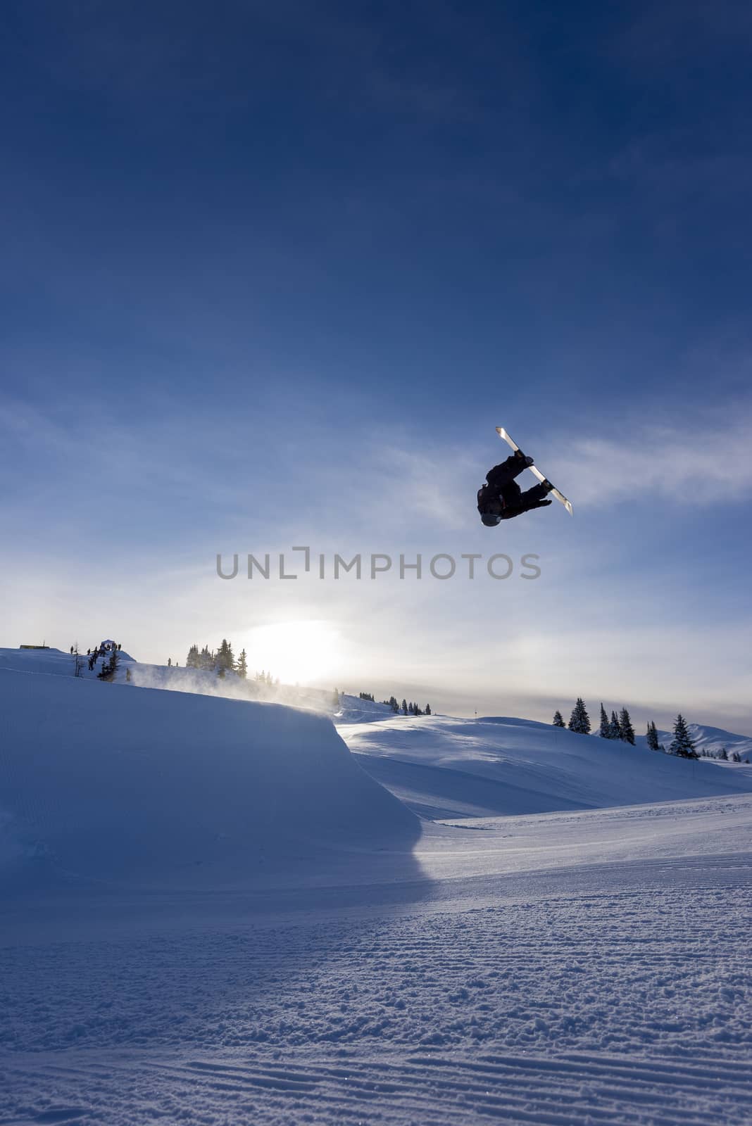 Snowboarder spinning doing a grab in the air off a jump