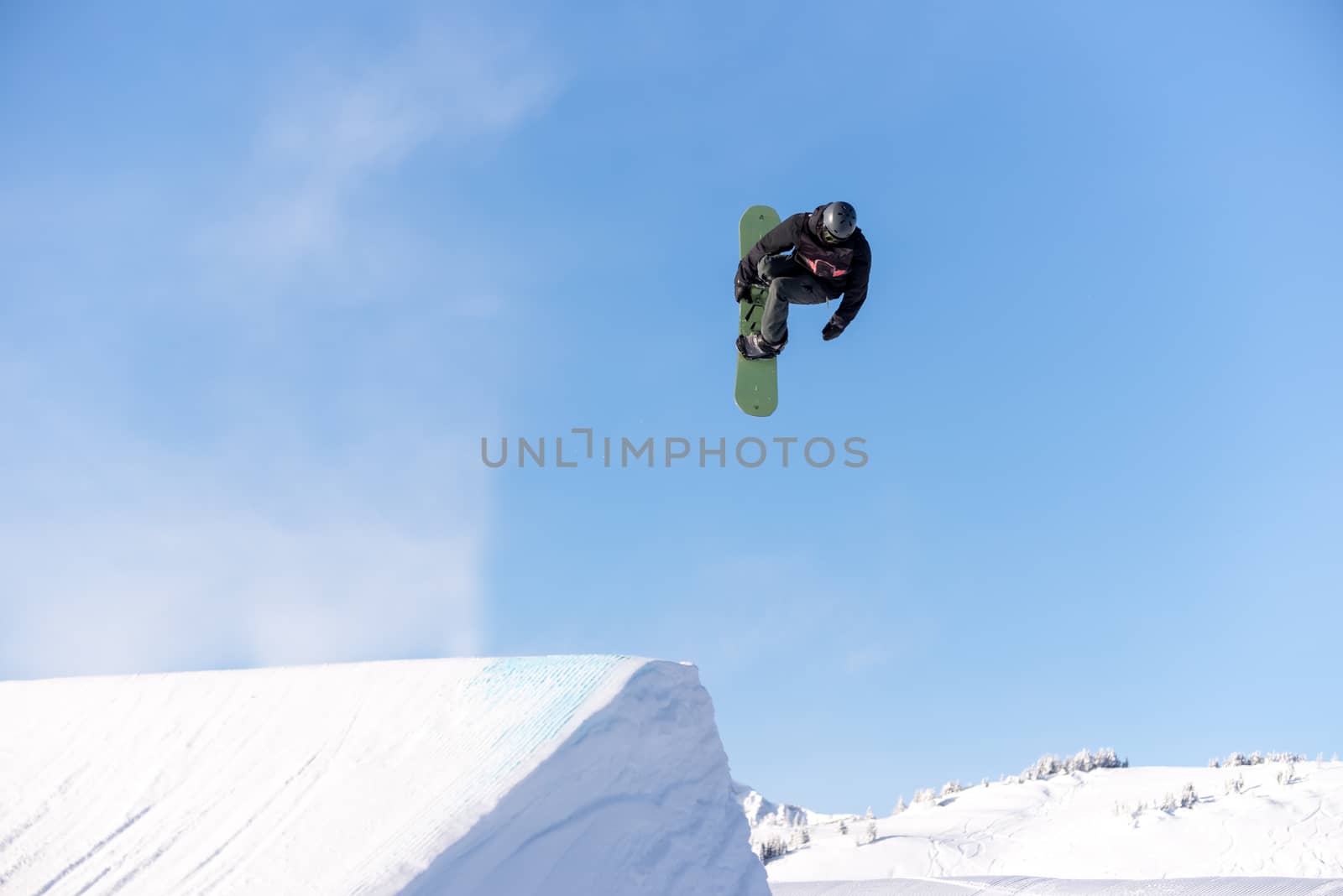 Snowboarder spinning doing a grab in the air off a jump