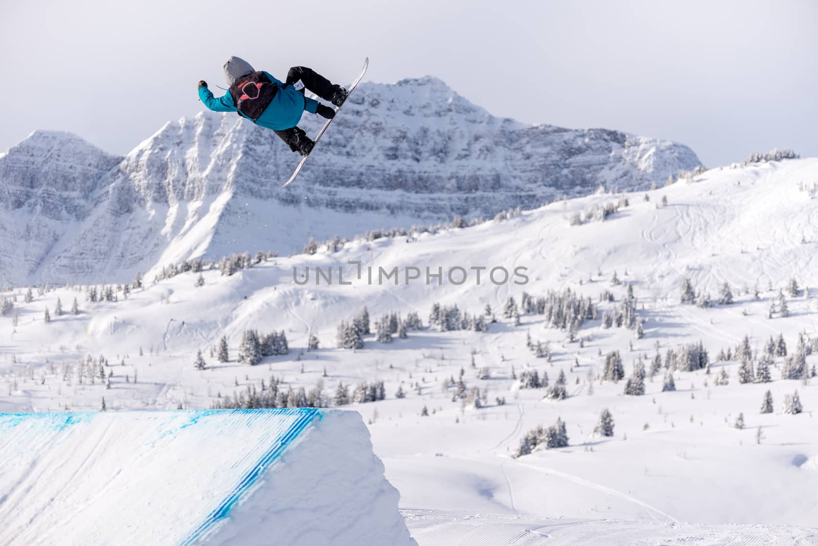 Snowboarder spinning doing a grab in the air off a jump