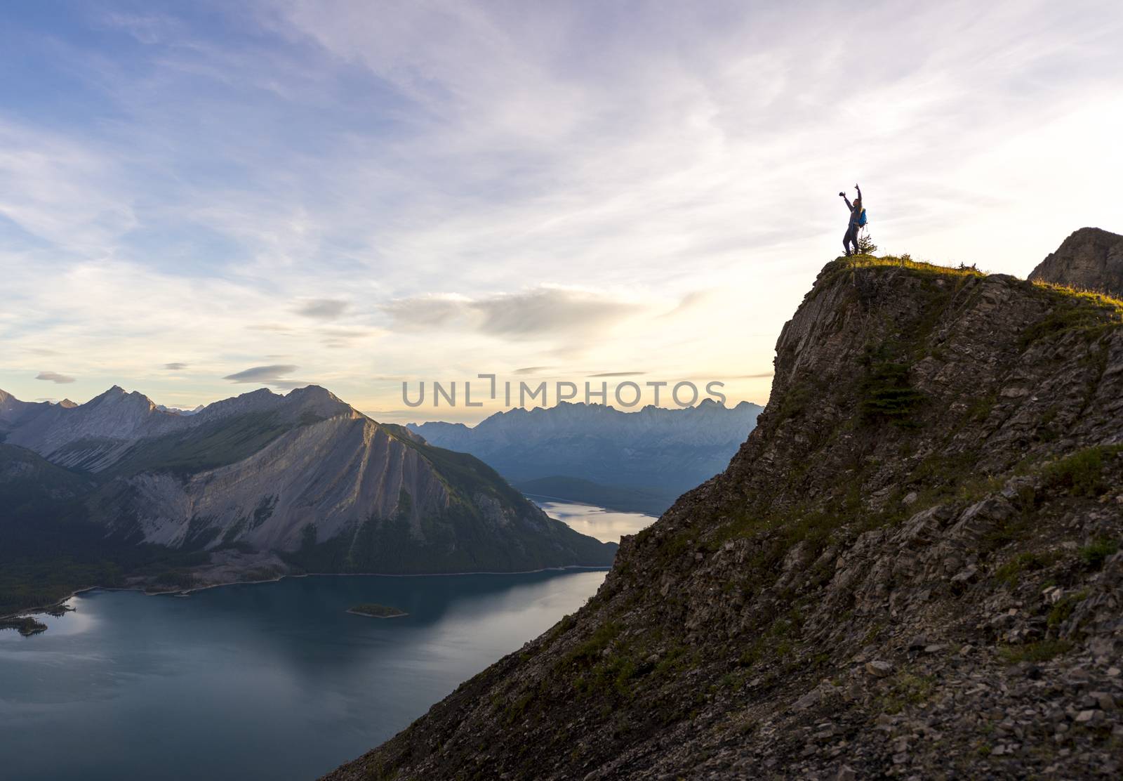 Young man celebrates successfully reaching the peak of a mountain