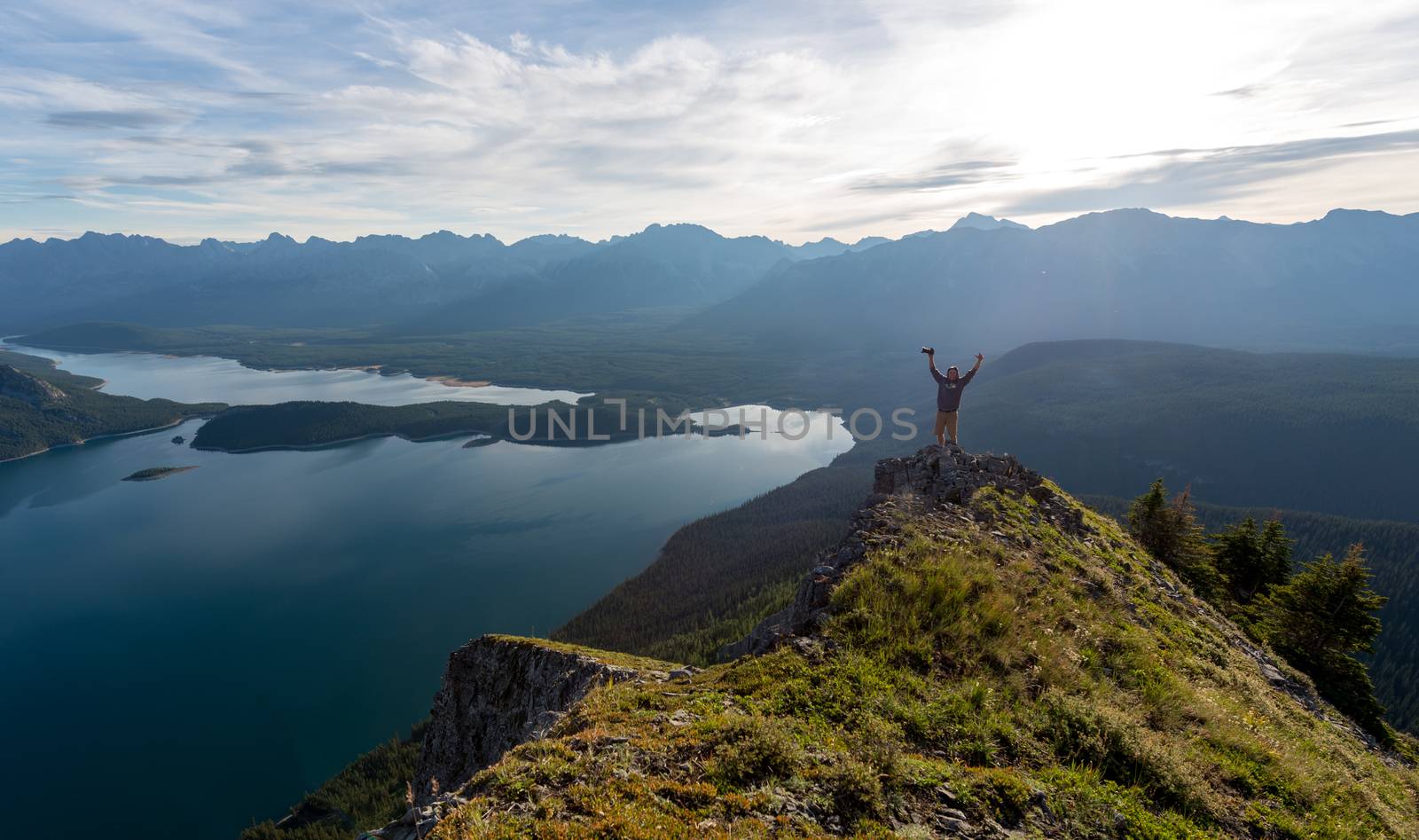 Young man celebrates successfully reaching the peak of a mountain