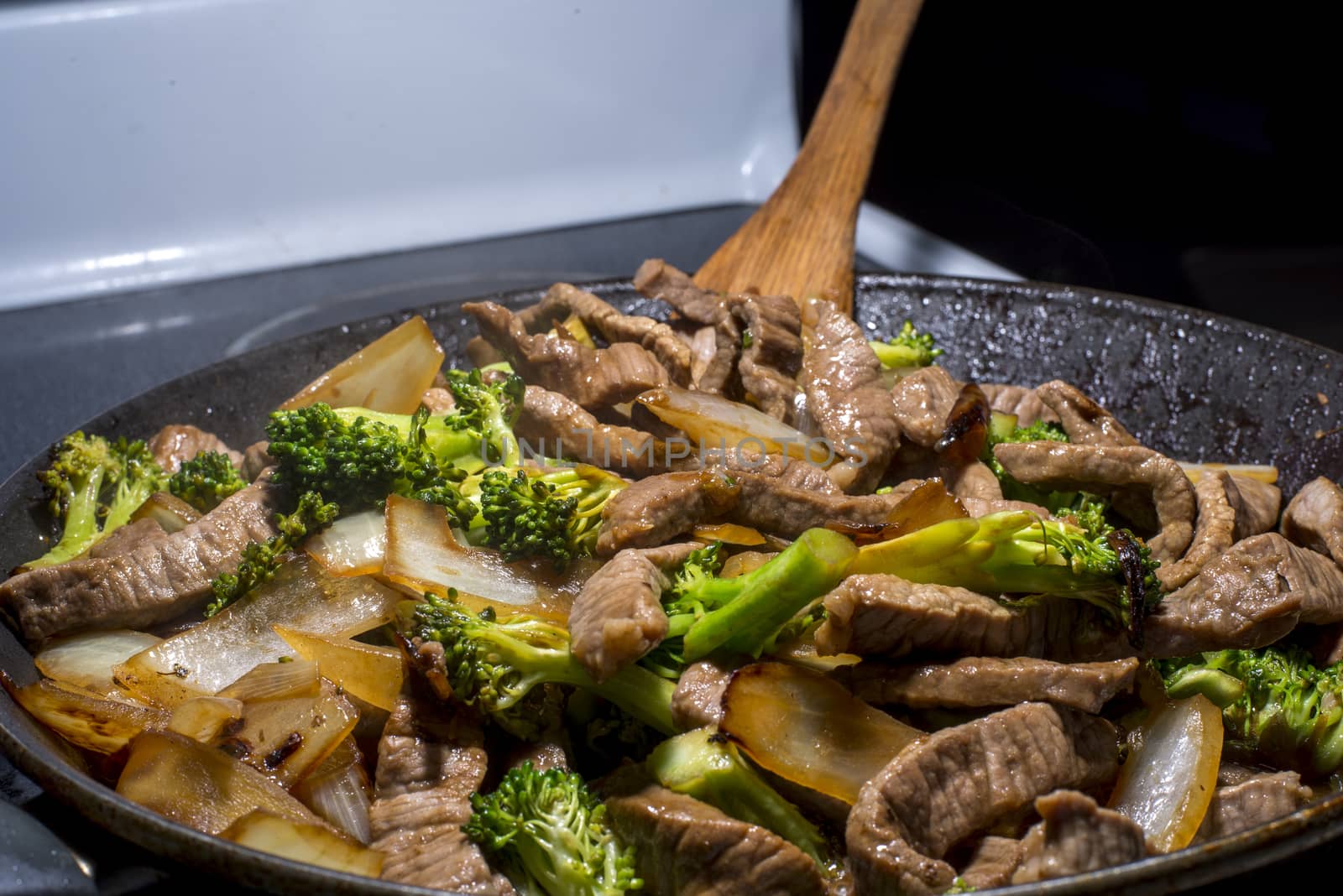 beef broccoli and onion stirfry steaming in a pan