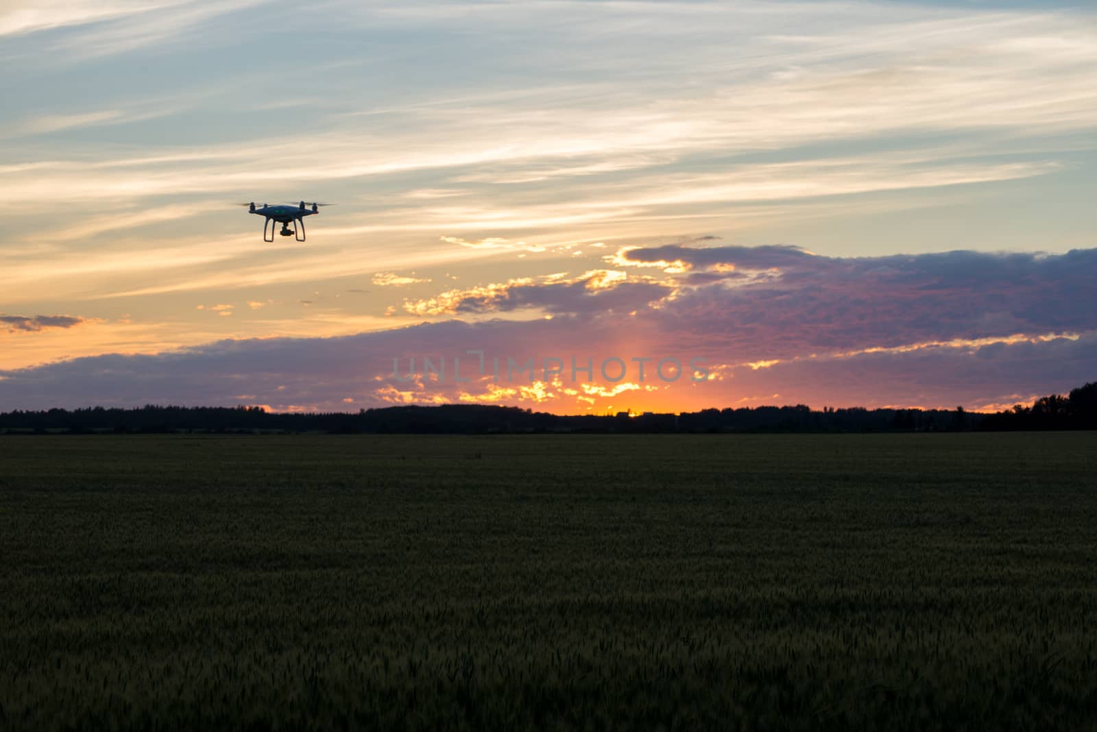 Drone silhouetted against orange sunset taking video