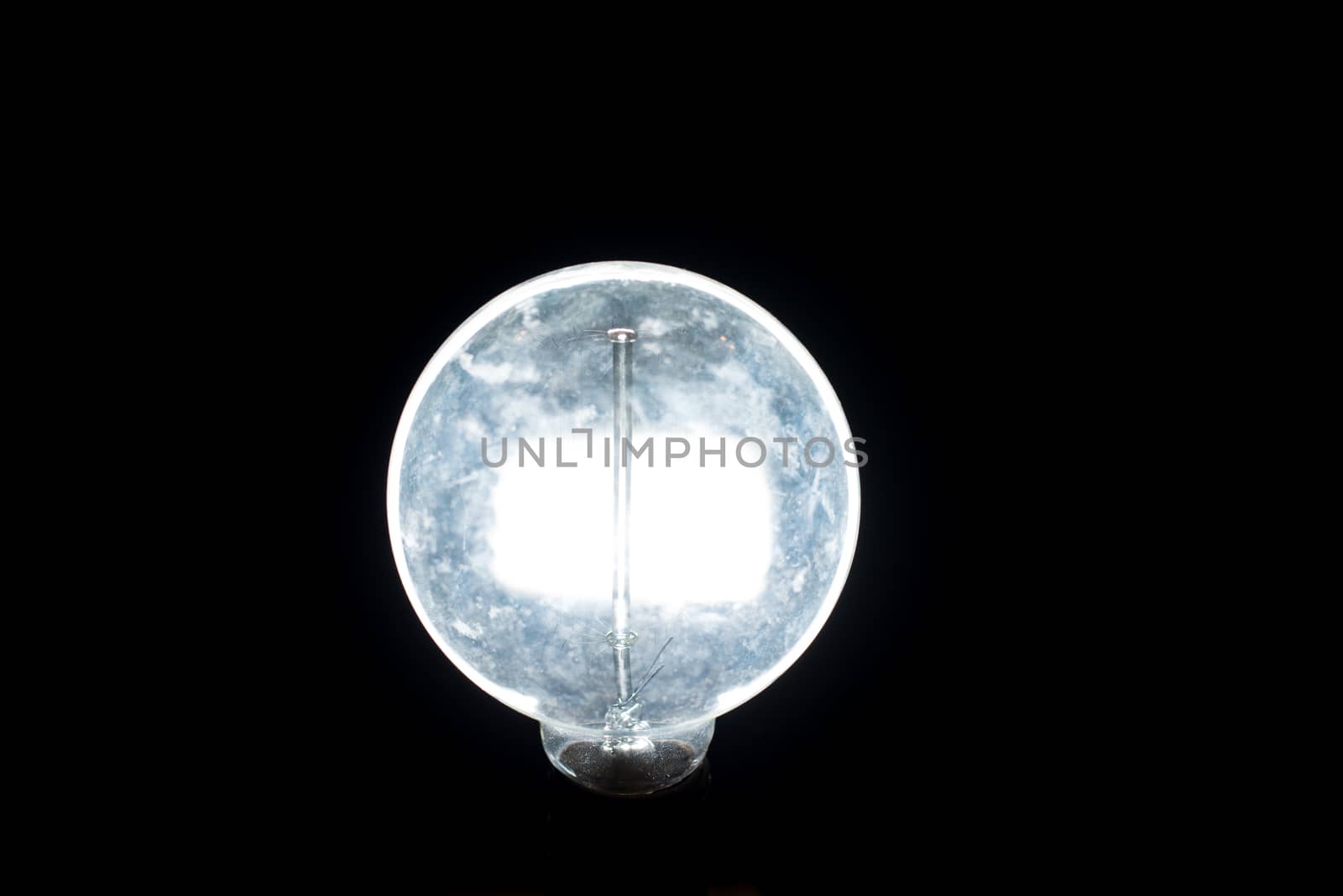 Antique lit light bulb isolated on black background