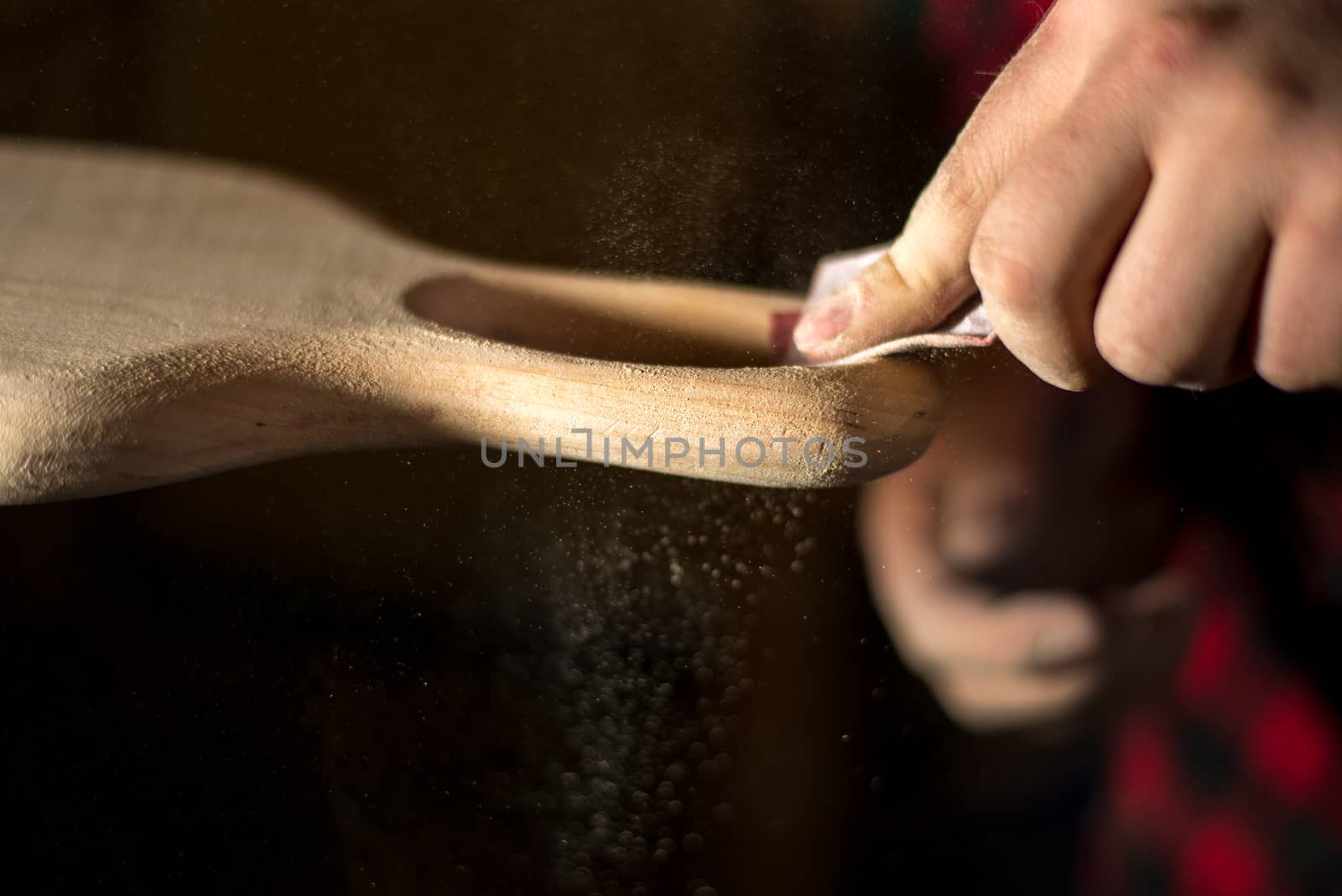 Hands manual sanding a wood cutting board handle