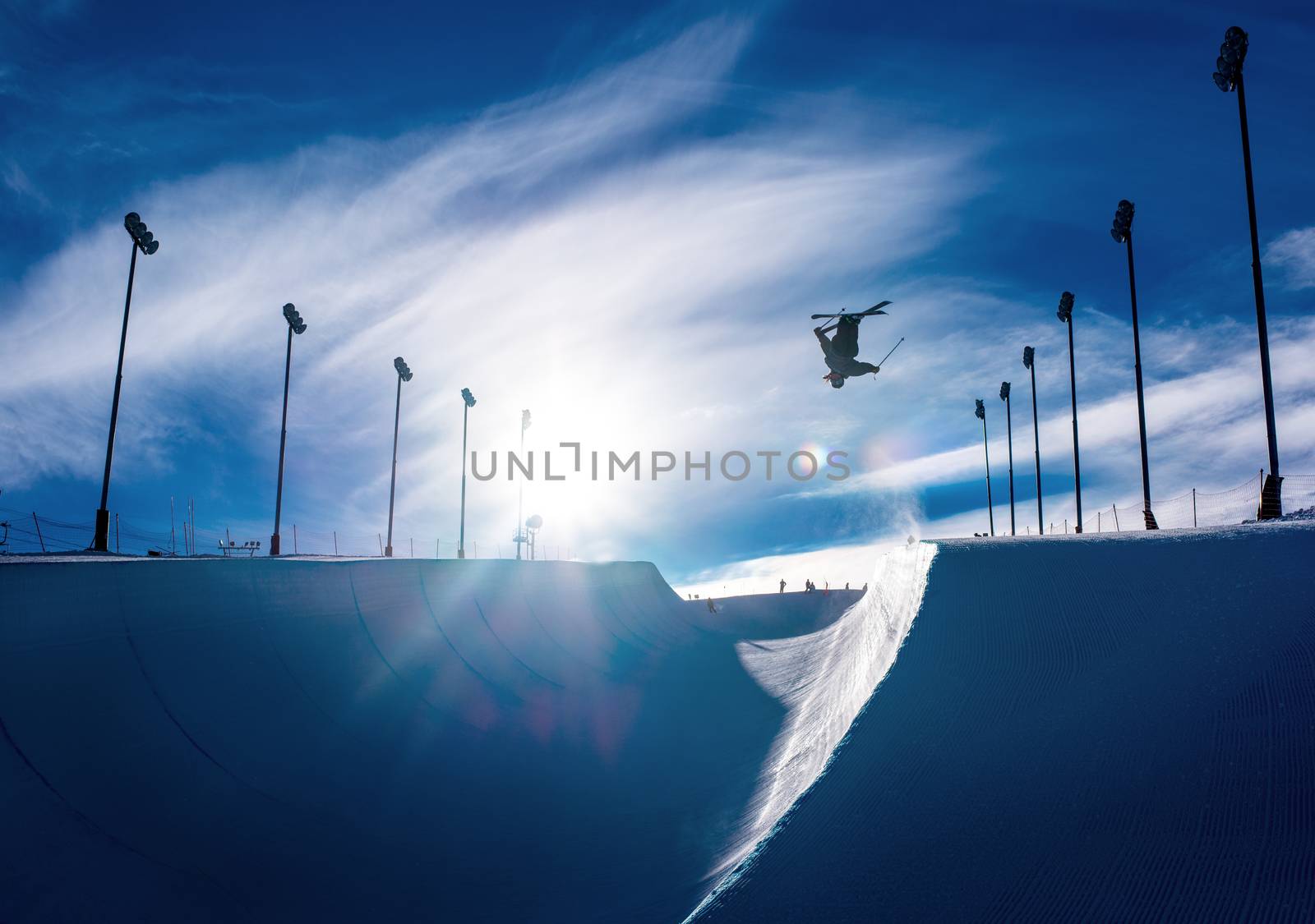 Skier doing an inverted trick in a winter snow halfpipe