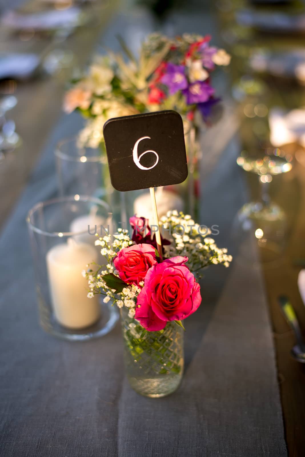 Table decorations at a wedding with candles, flowers and a number