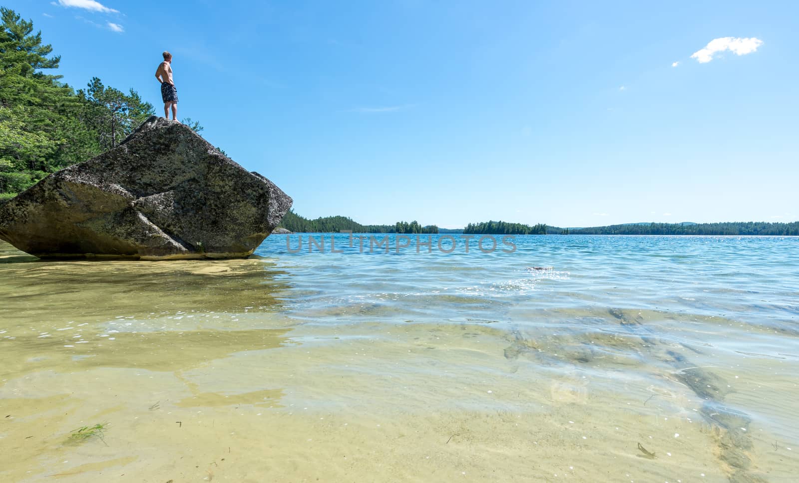 Man standing on a rock on a beach on a warm summer day