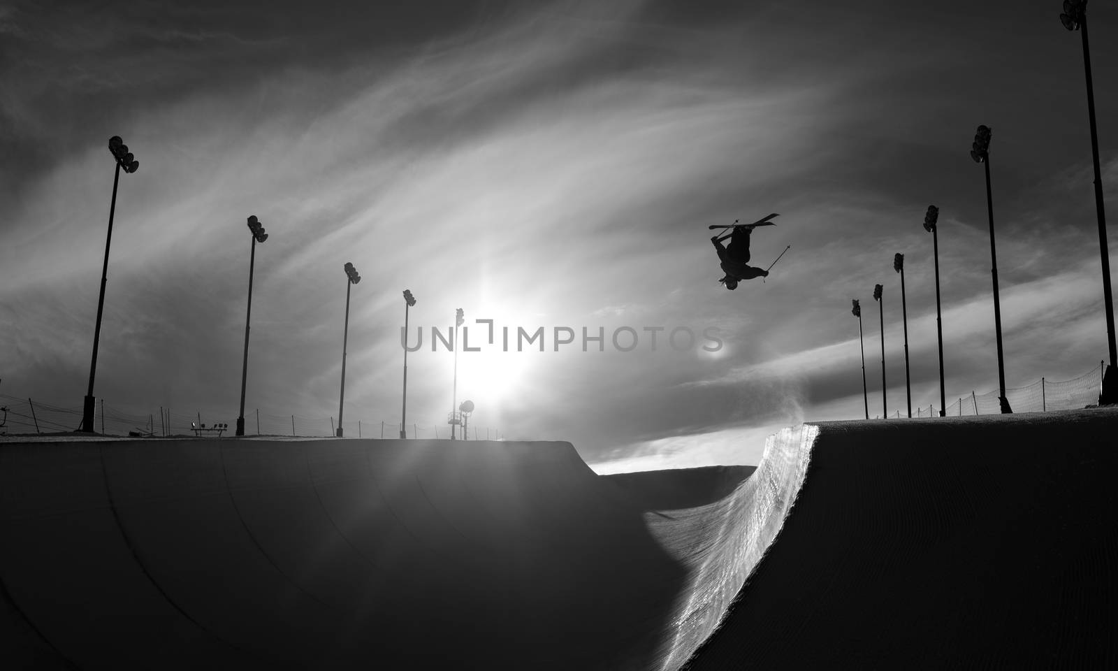 Skier doing an inverted trick in a winter snow halfpipe