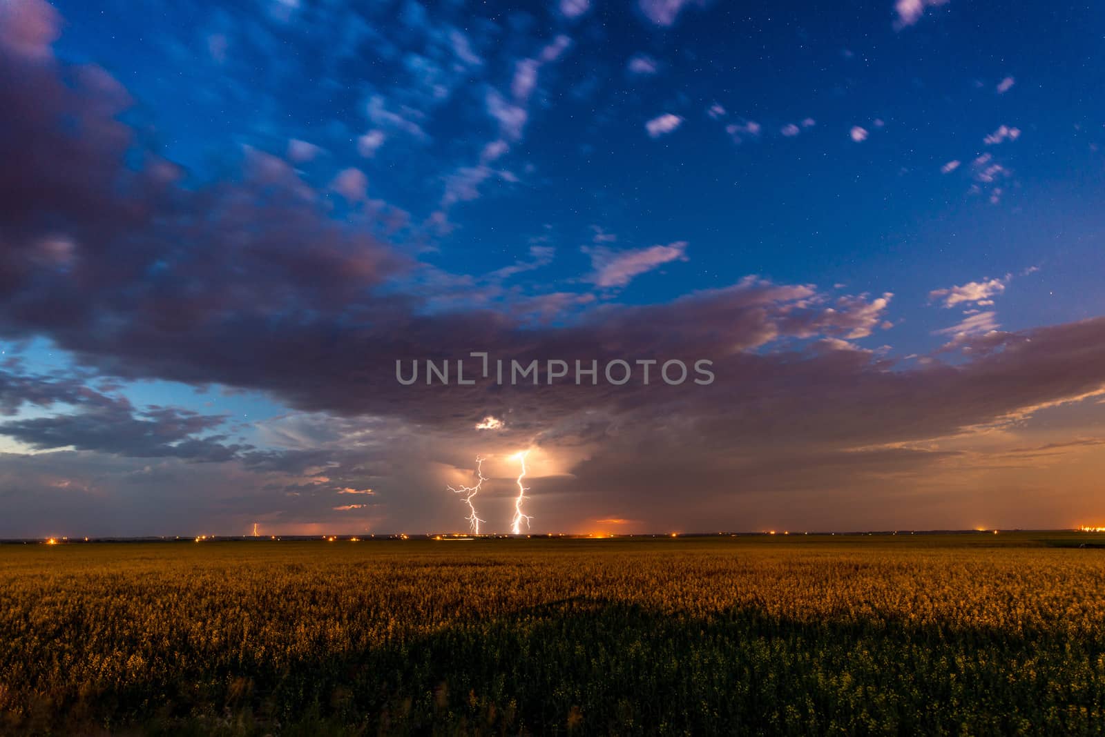 Lightning bolt from clouds over a farm field with stars
