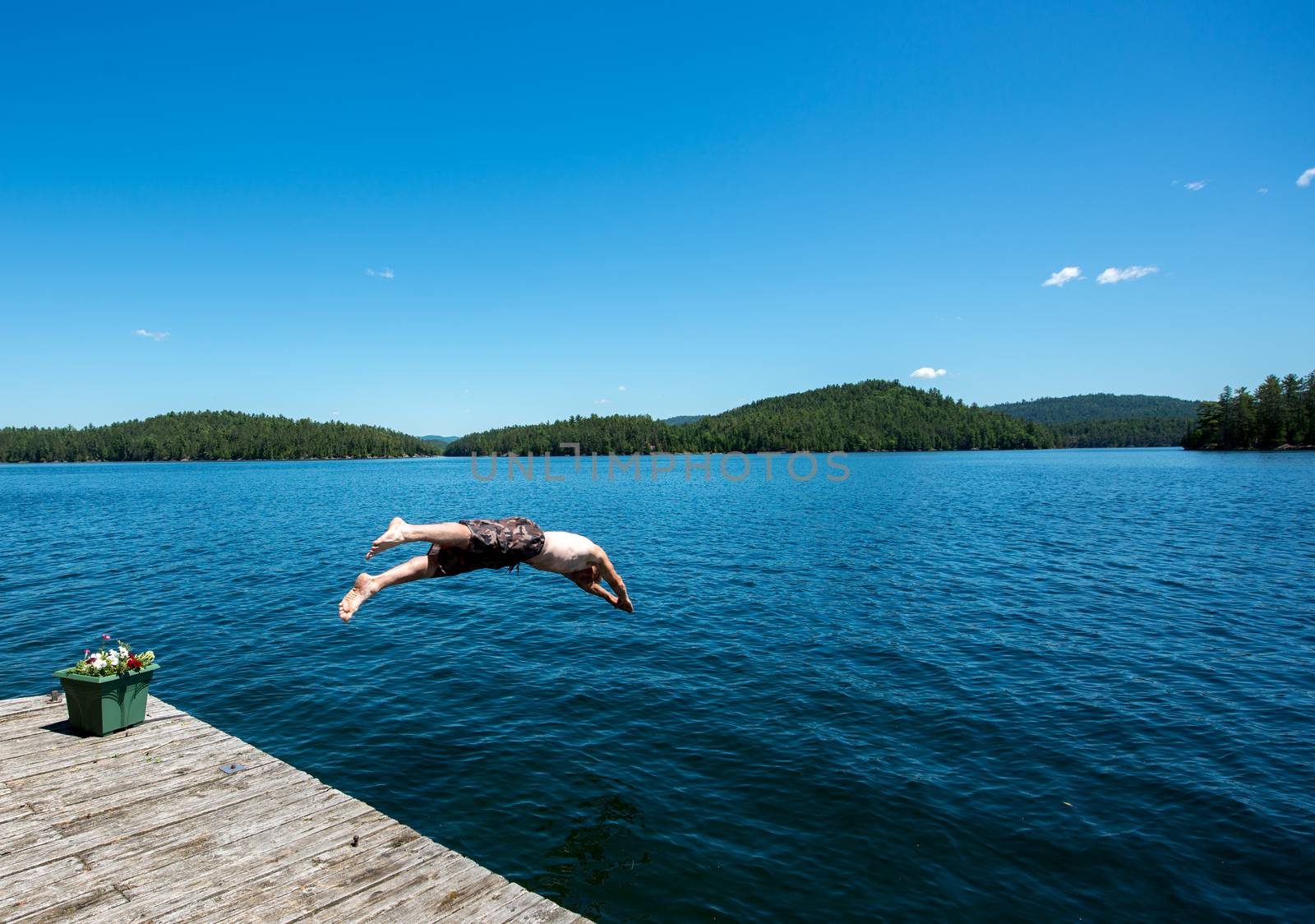 One young caucasian man diving into a lake in the summer by TSLPhoto