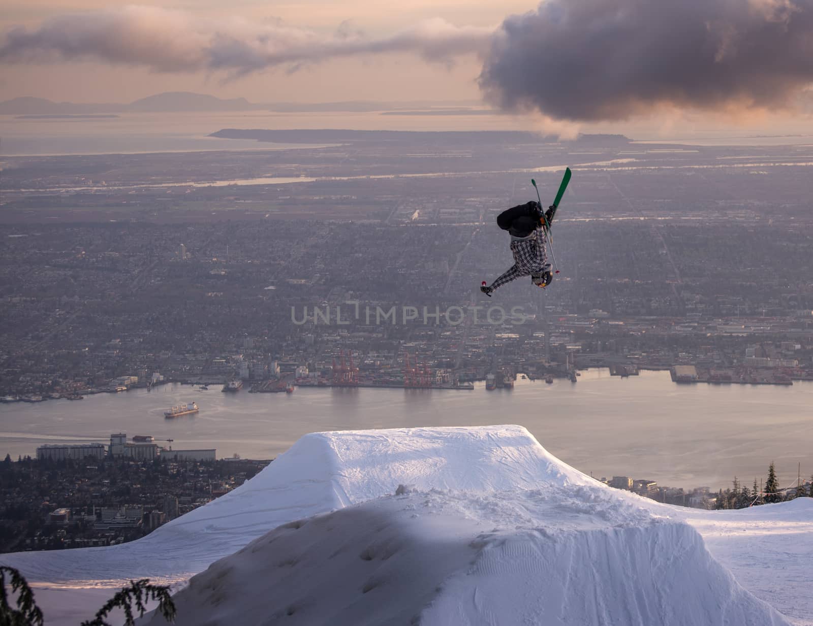 Freestyle skier performs backflip mute grab on jump above city by TSLPhoto