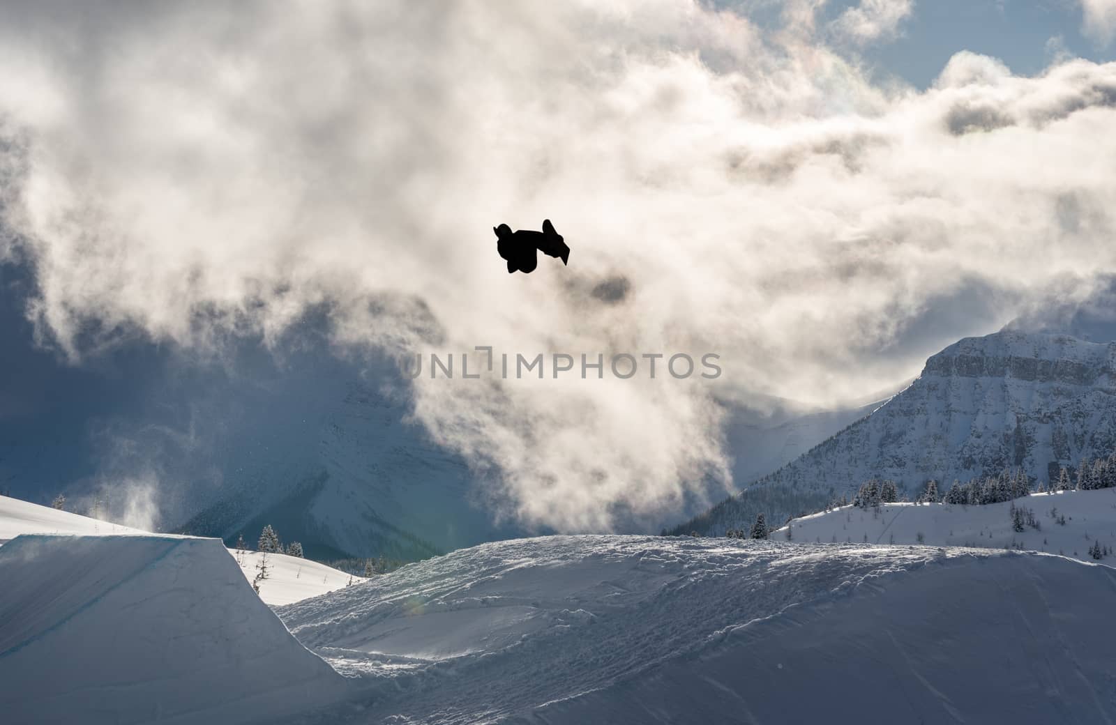 Snowboarder performing flip off a large jump in the mountains by TSLPhoto