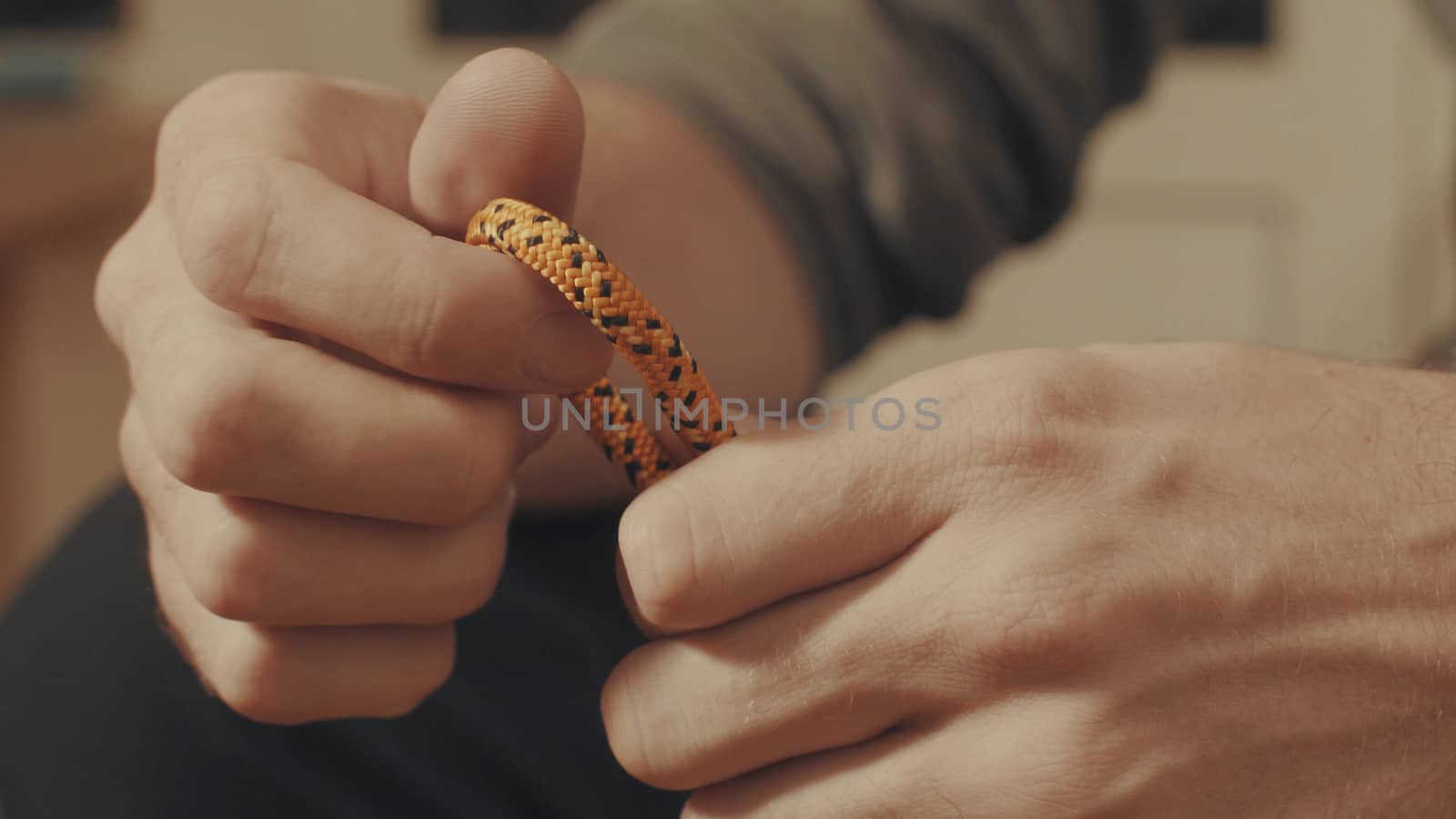 Man's hands tying a mountaineering knot on a rope. Close up.