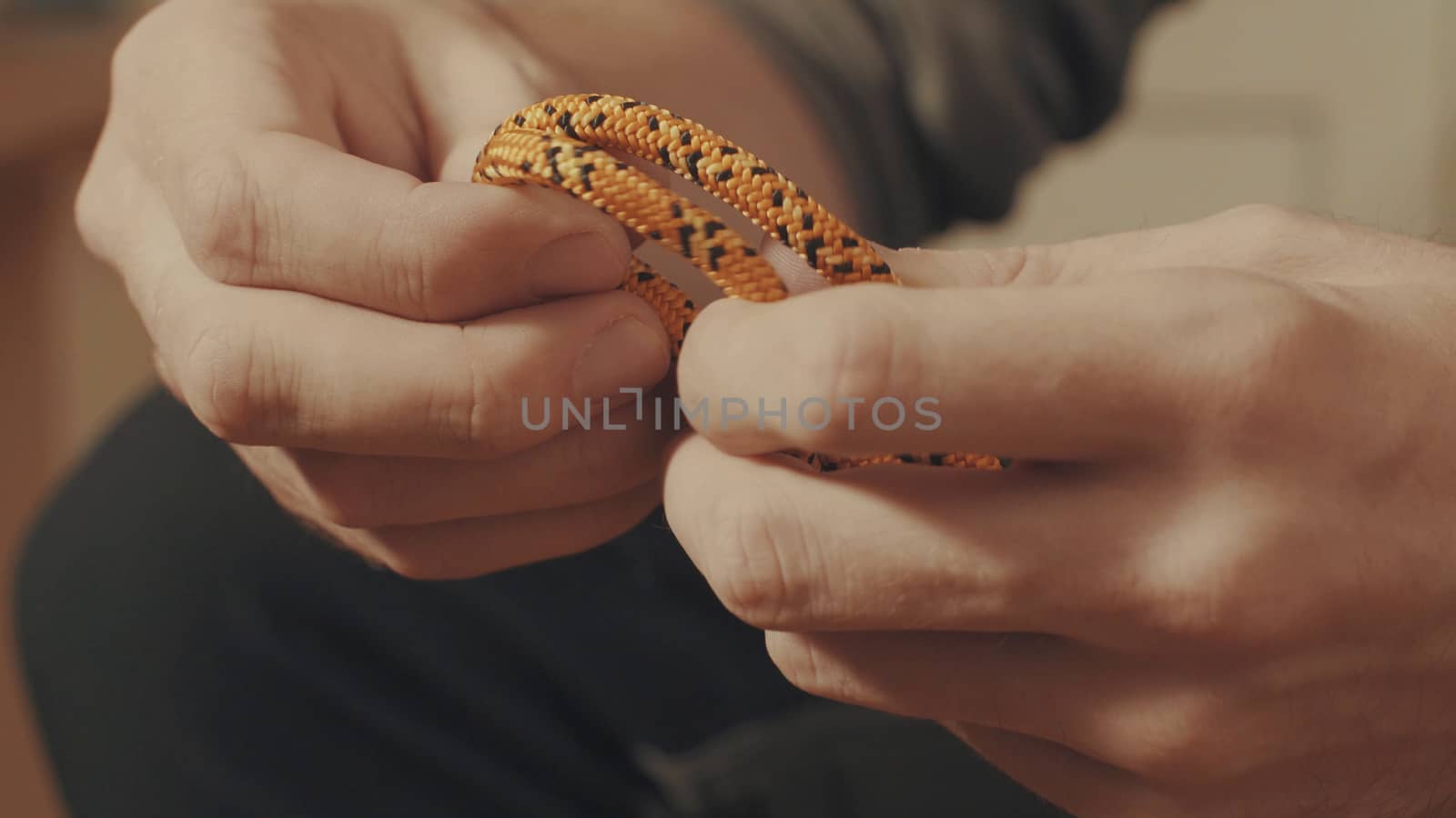 Man's hands tying a mountaineering knot on a rope. Close up.