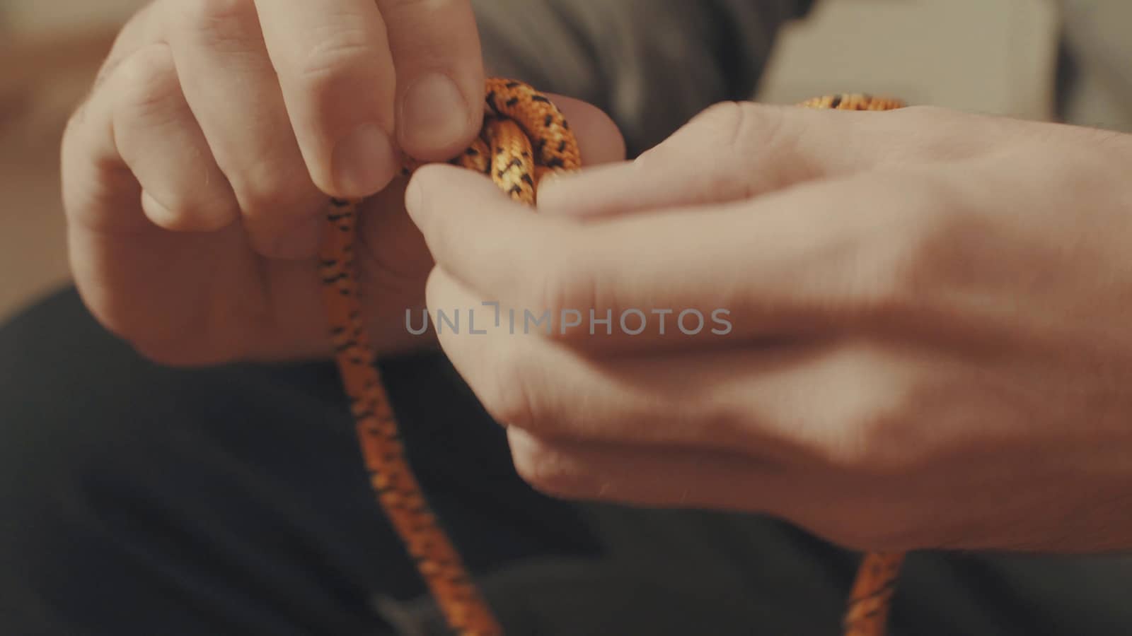 Man's hands tying a mountaineering knot on a rope. Close up.
