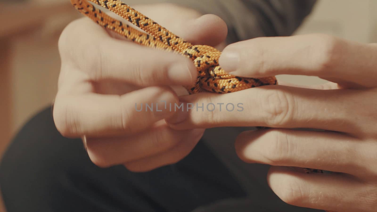 Man's hands tying a mountaineering knot on a rope. Close up.