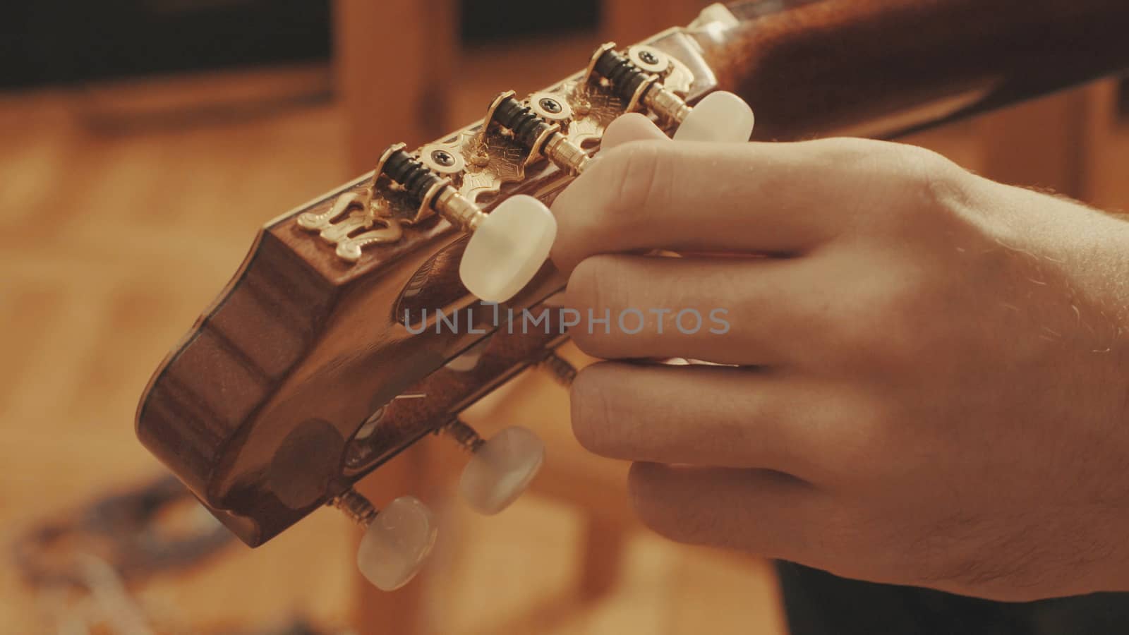 Guitarist's hands tuning the acoustic guitar close-up