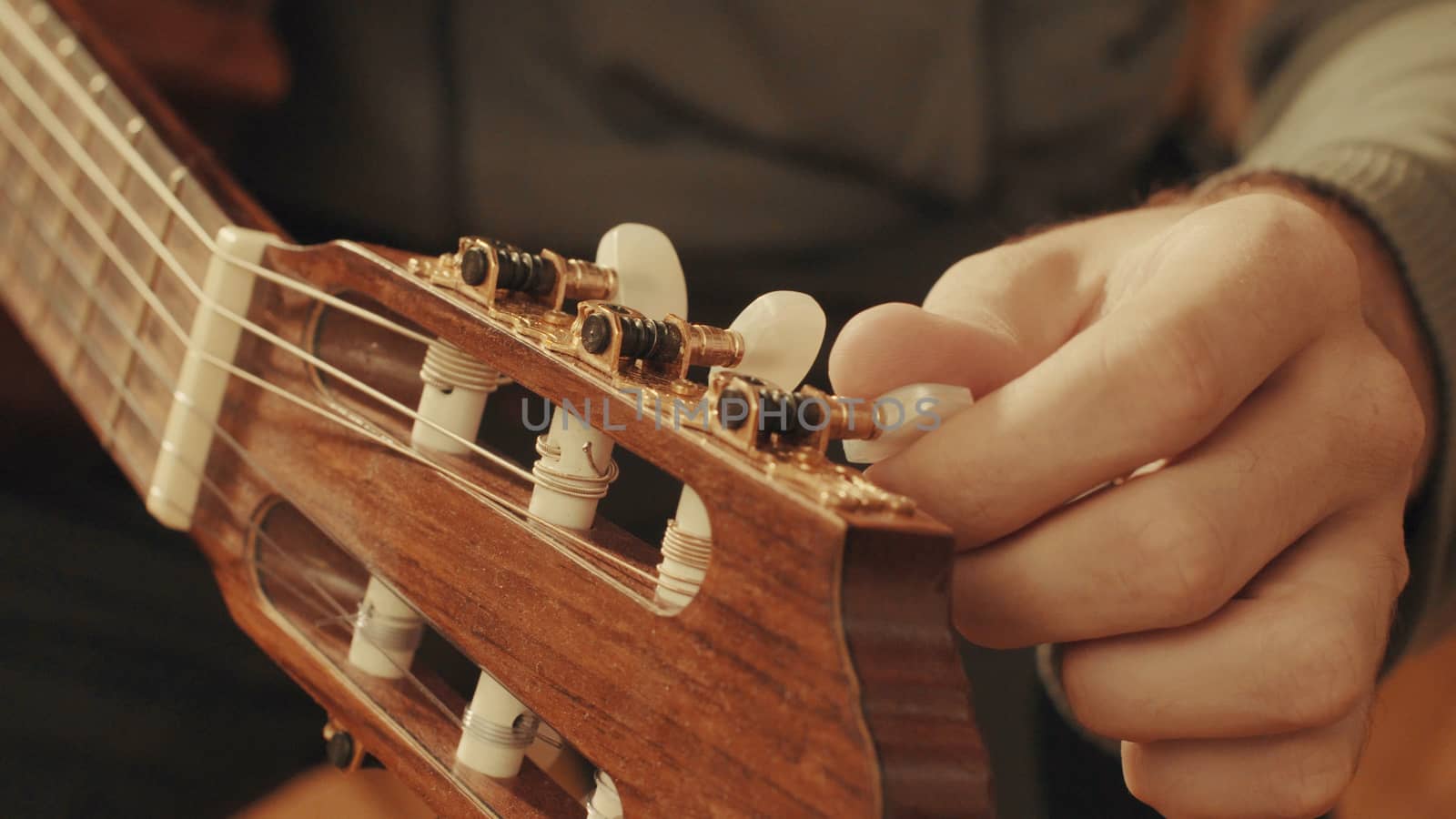 Guitarist's hands tuning the acoustic guitar close-up